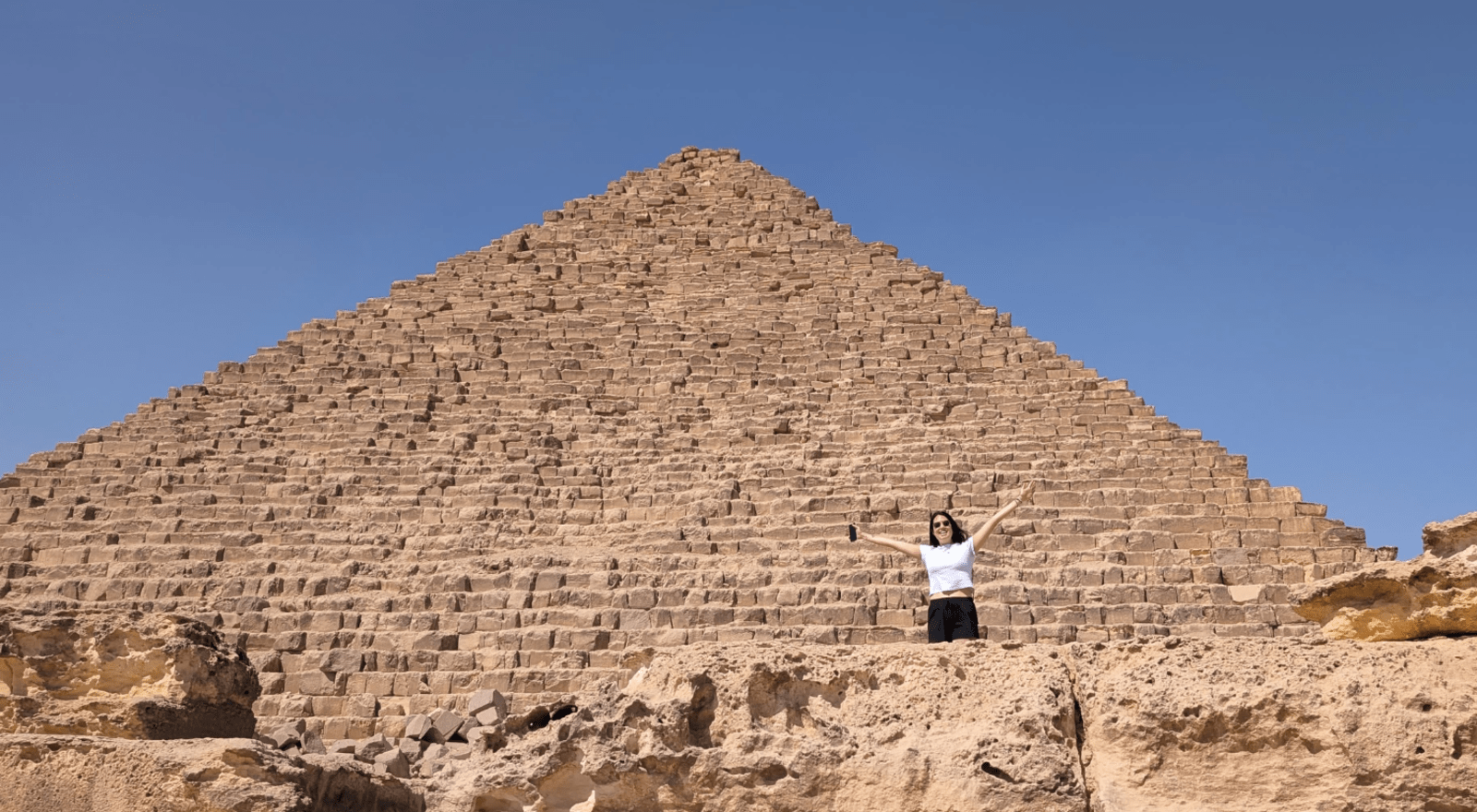 Sara Winfield stands and waves from below one of the Great Pyramids of Giza