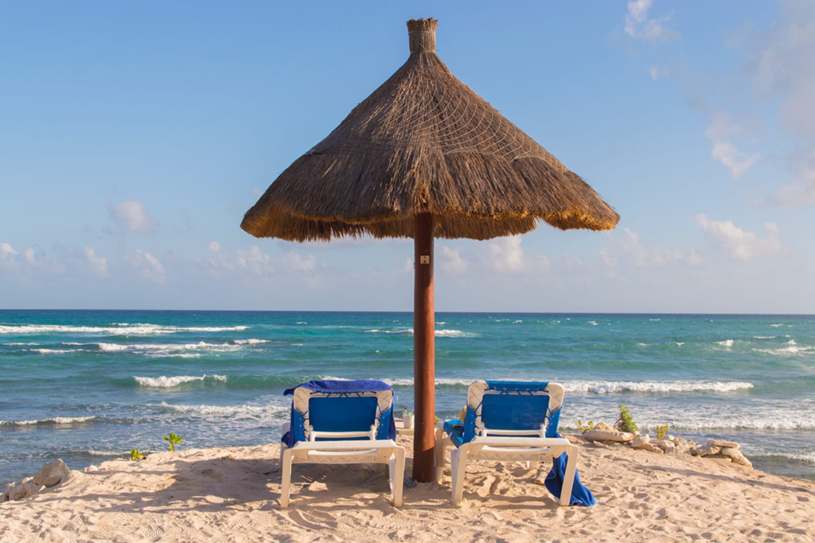 Lounger underneath a palapa on a beach in Mexico