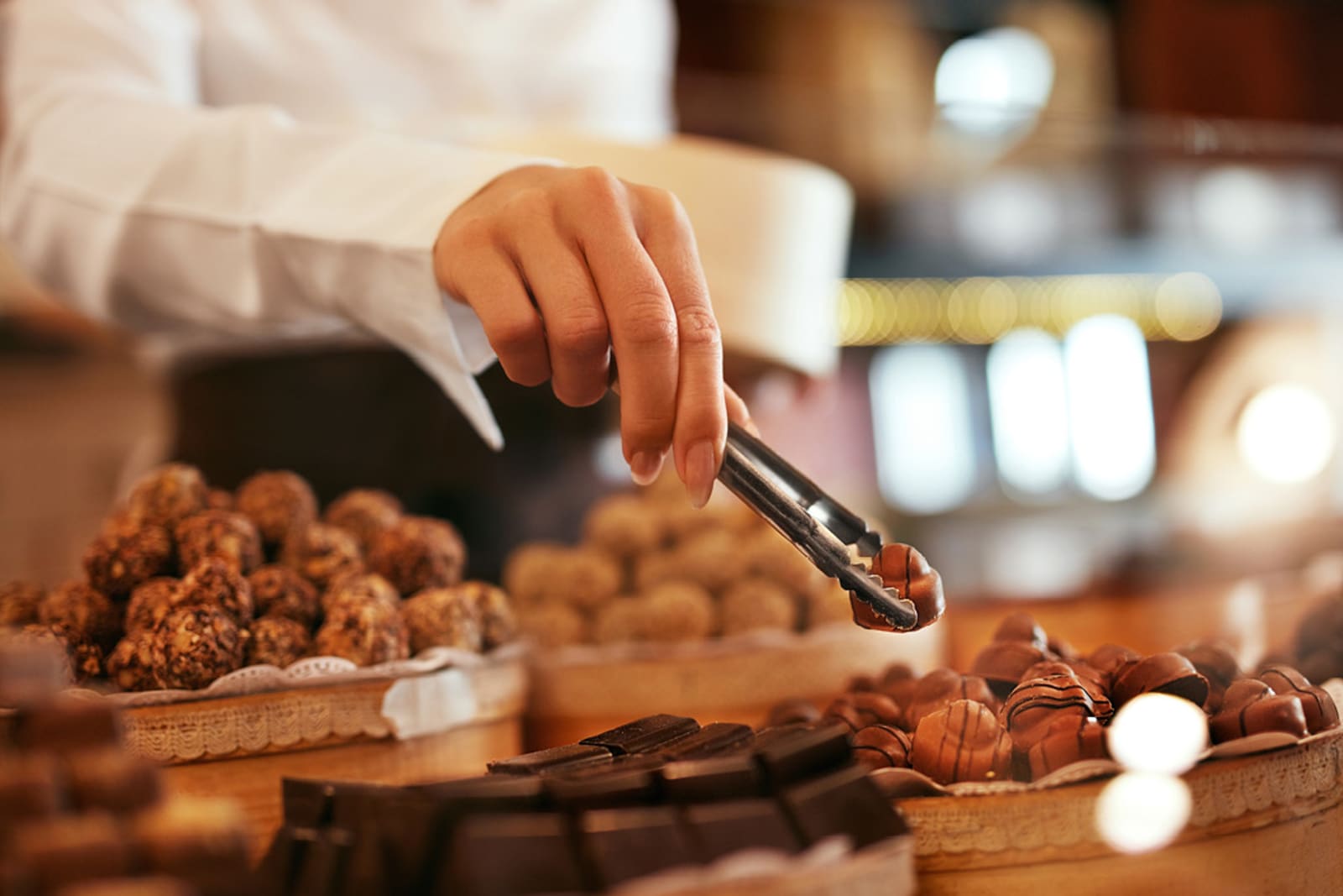 A chocolatier carefully placing chocolates in a shop display
