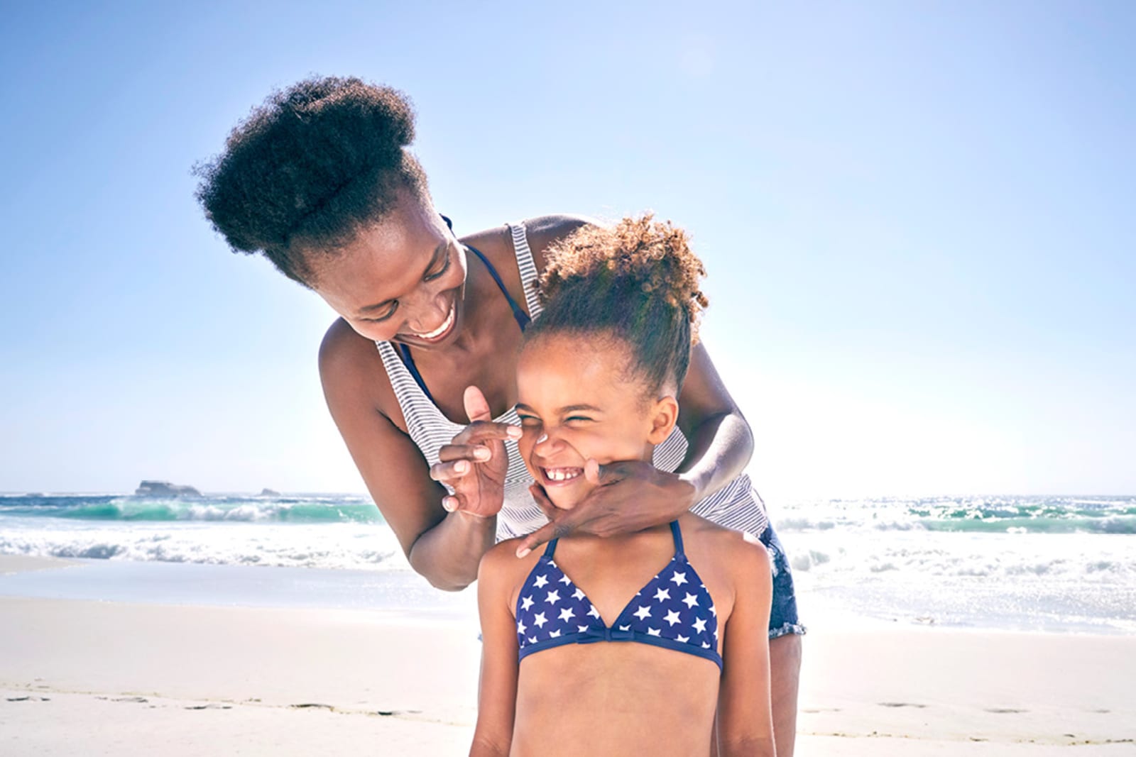 Woman applying sunscreen to her daughter's nice on a beach in Mexico