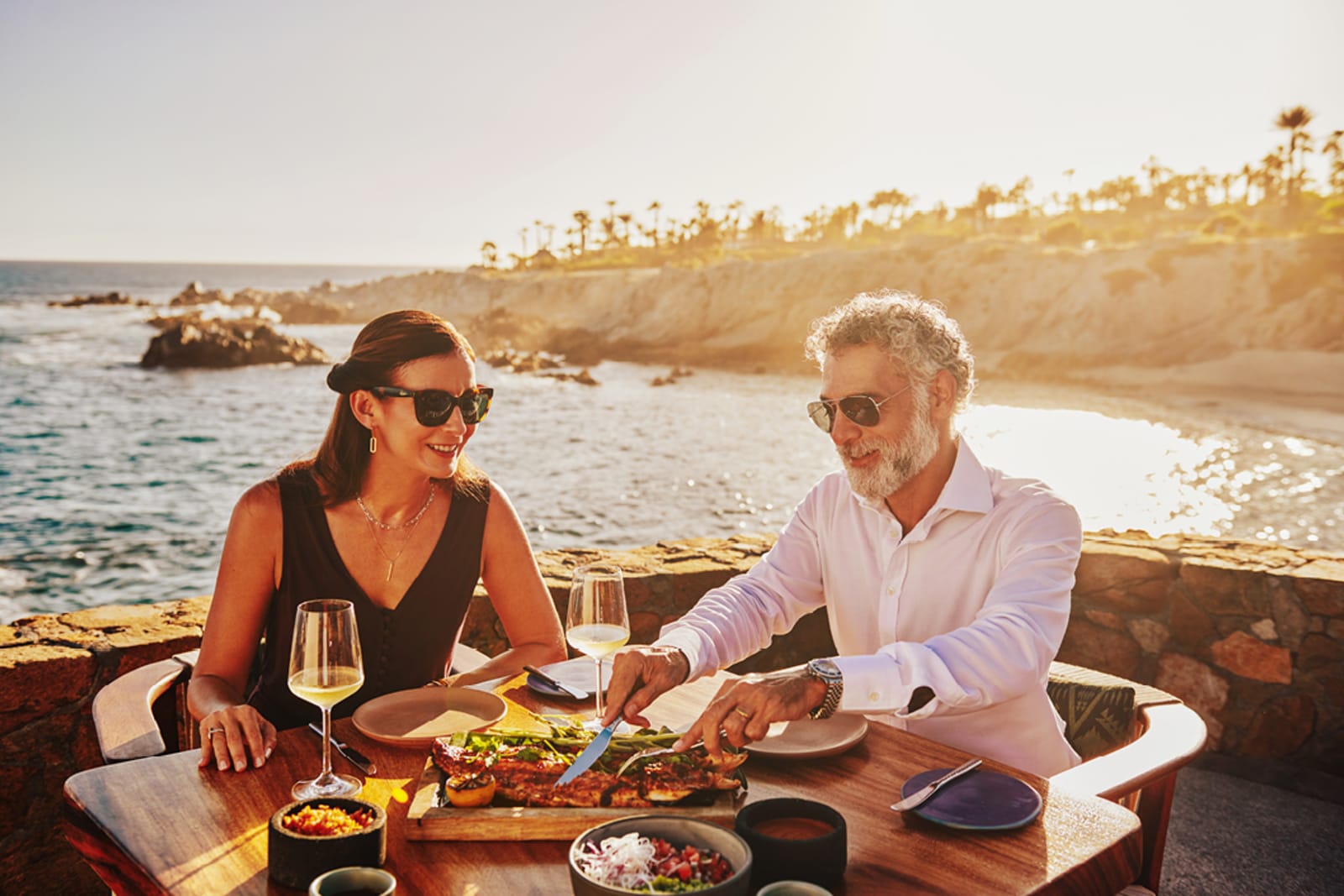 A woman and man at a table eating local cuisine in Los Cabos