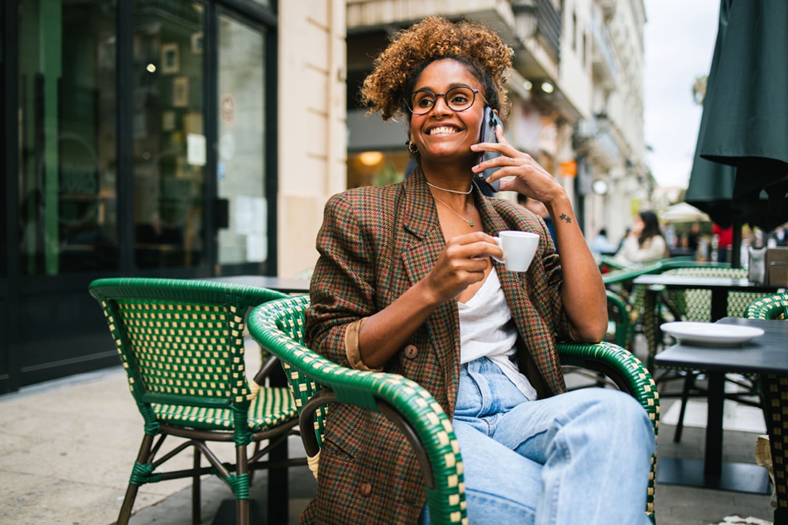A woman talking on her phone while sitting at a European cafe