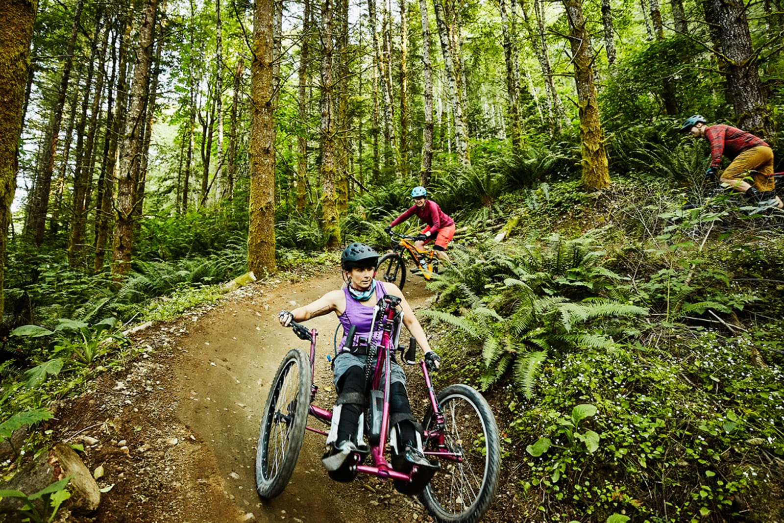 A small group of travellers mountain biking; one of them is using a handcycle