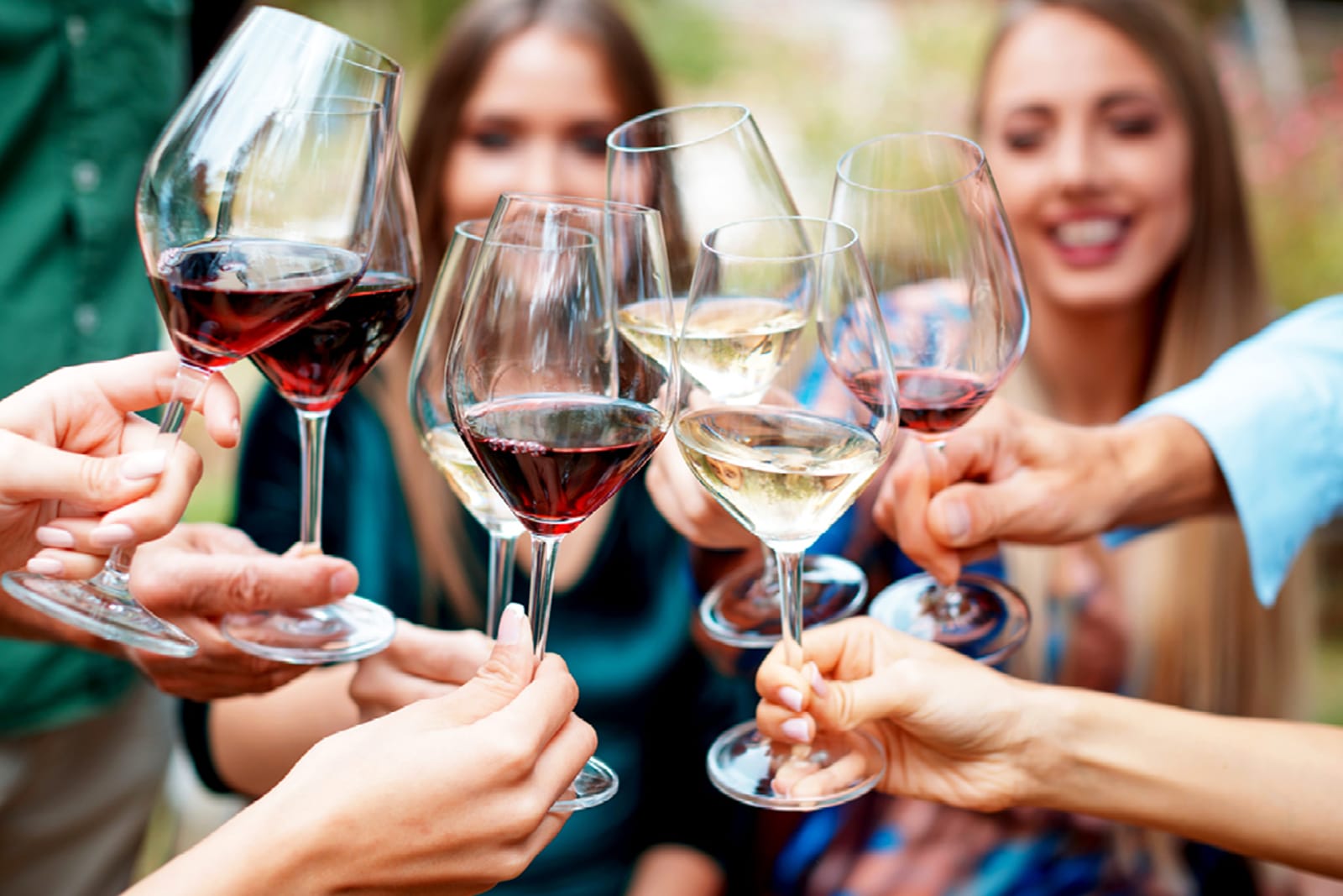 A group of people cheersing glasses of red and white wine