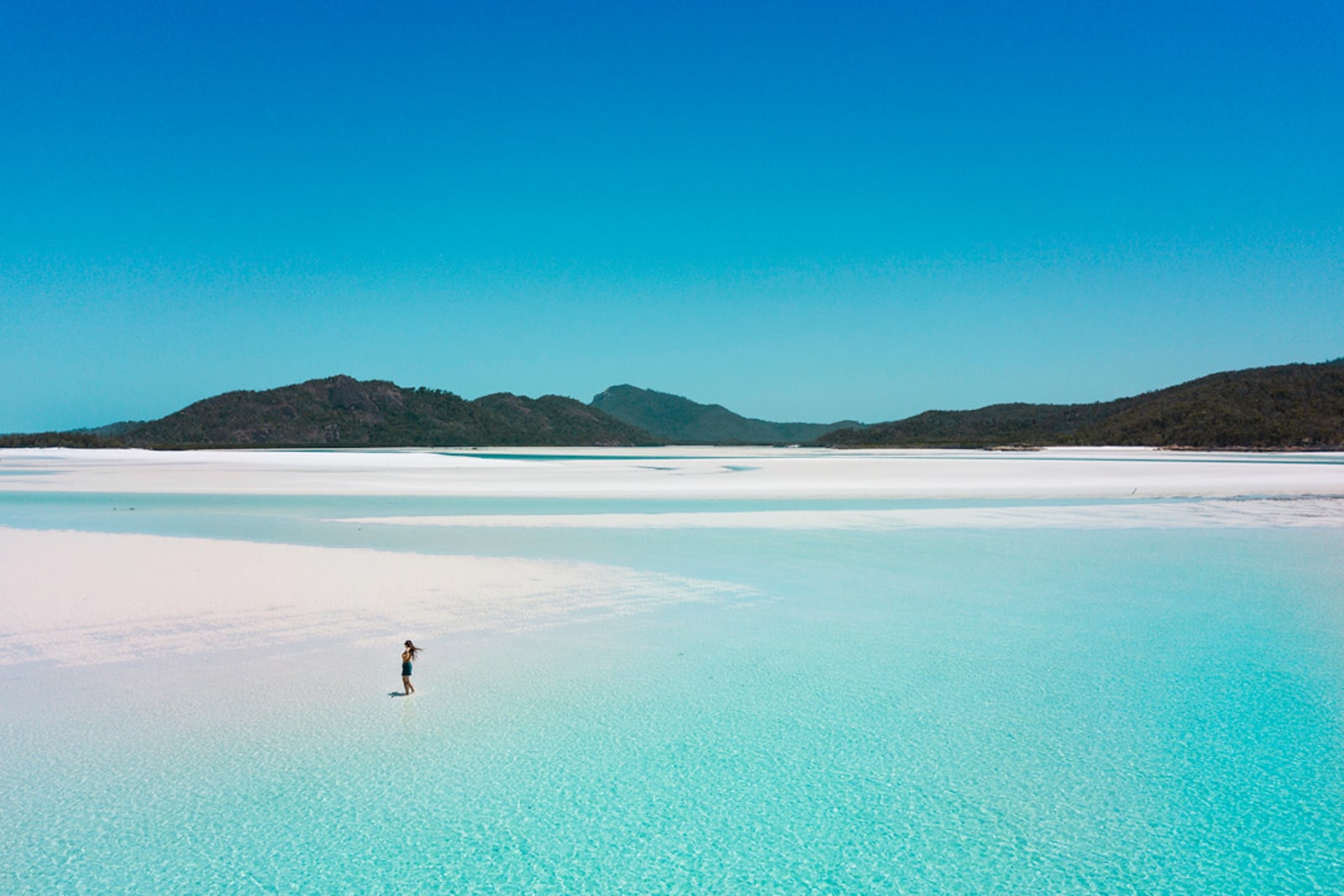 A traveller standing on Whitehaven Beach, Whitsunday Islands
