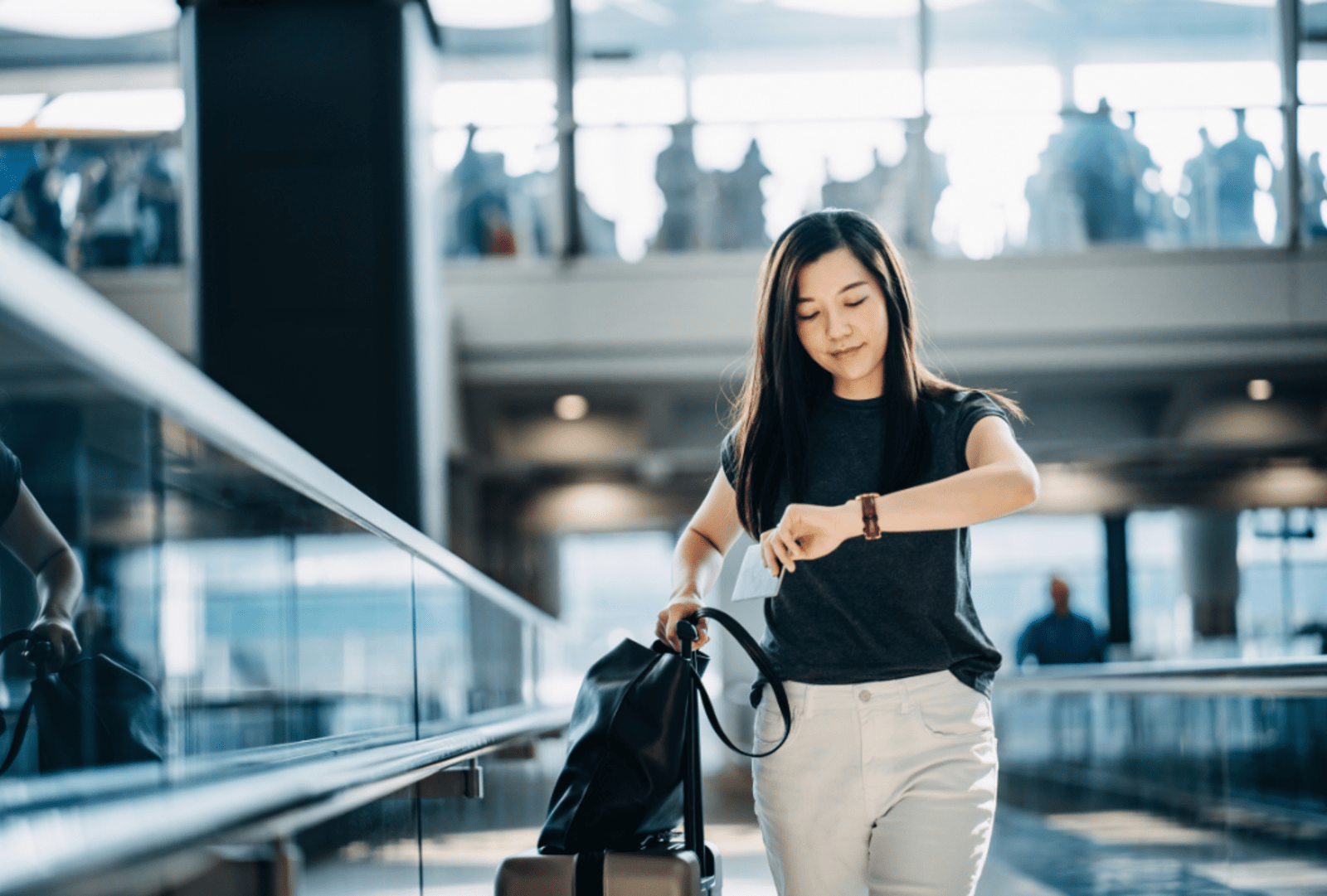 A businesswoman checks her watch while standing on an airport escalator 