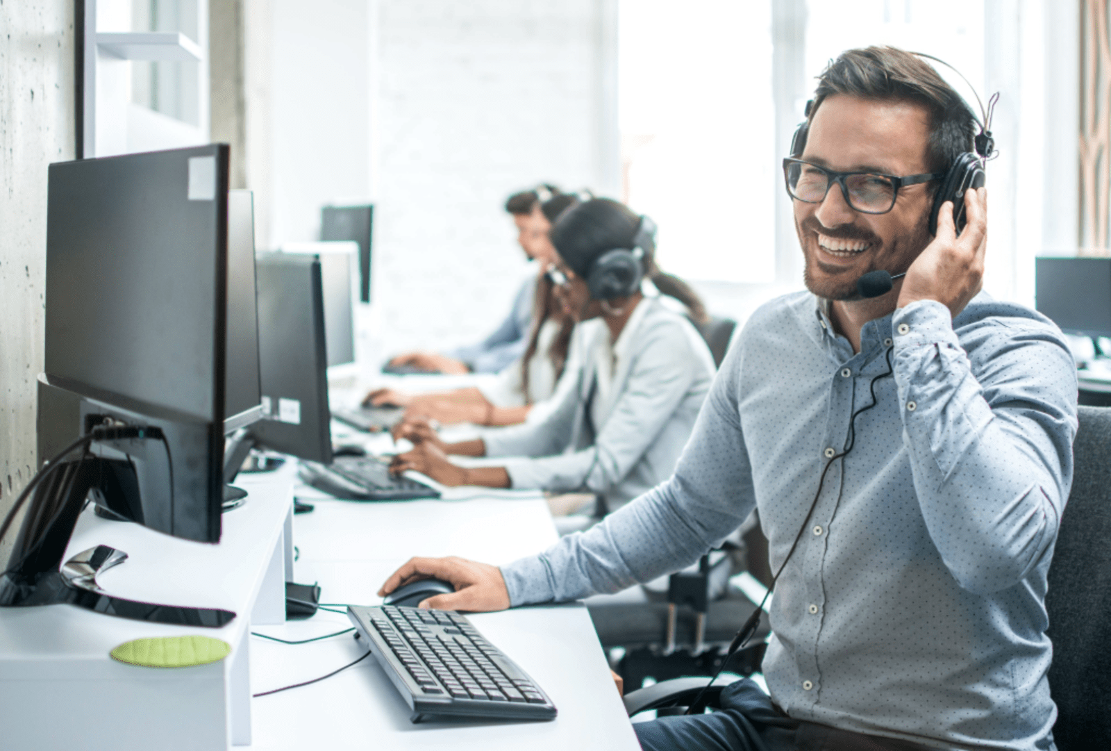 A man smiles as he chats into a headset