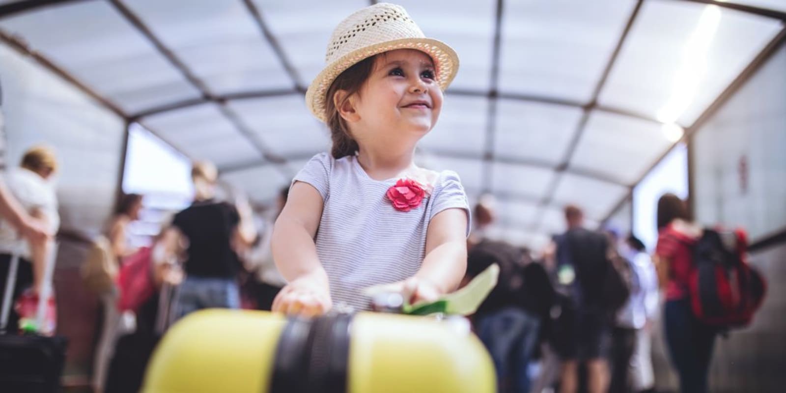 A young child in an airport pushing a suitcase