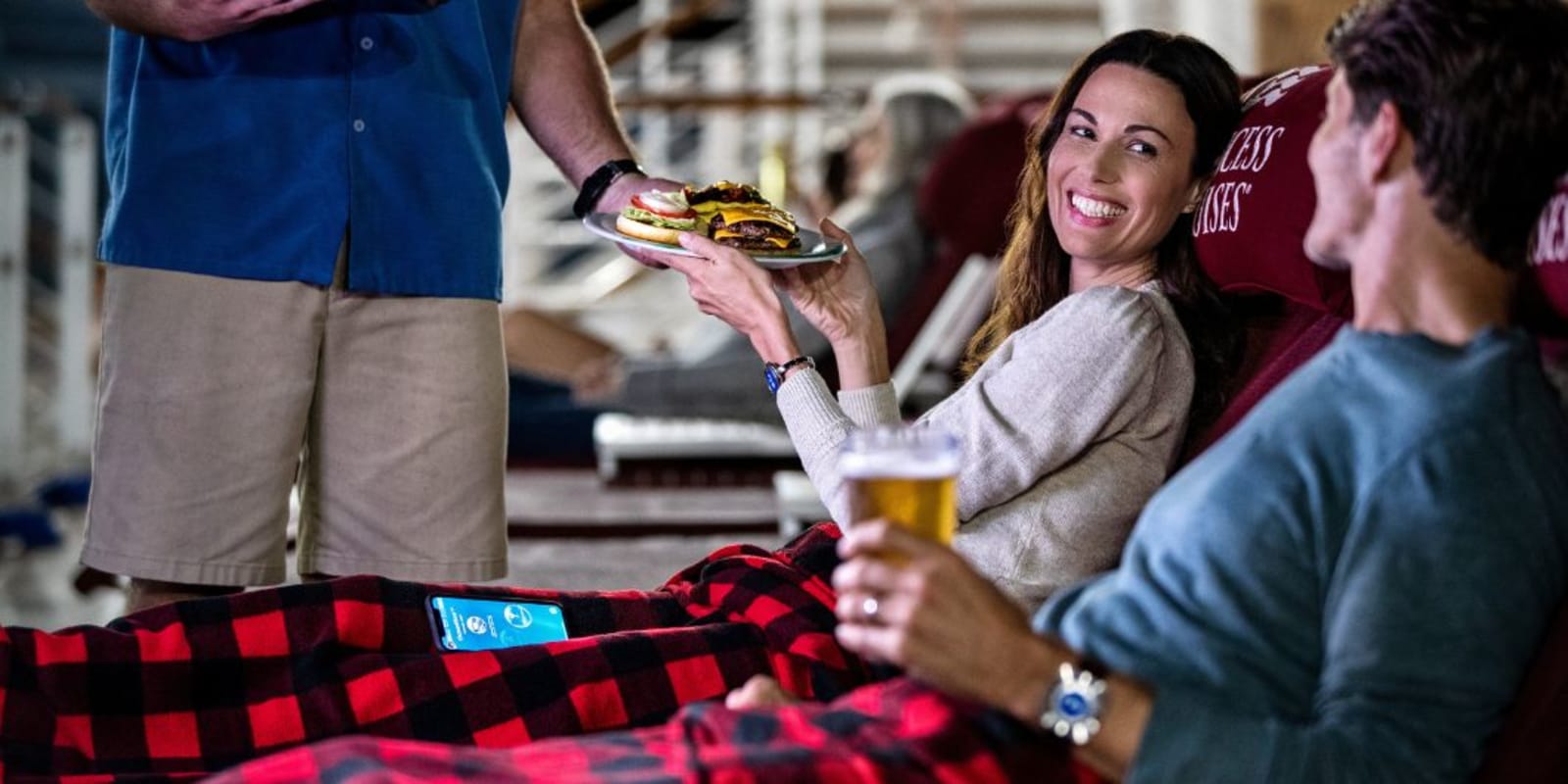 A couple getting food delivered to their deck chair on a cruise