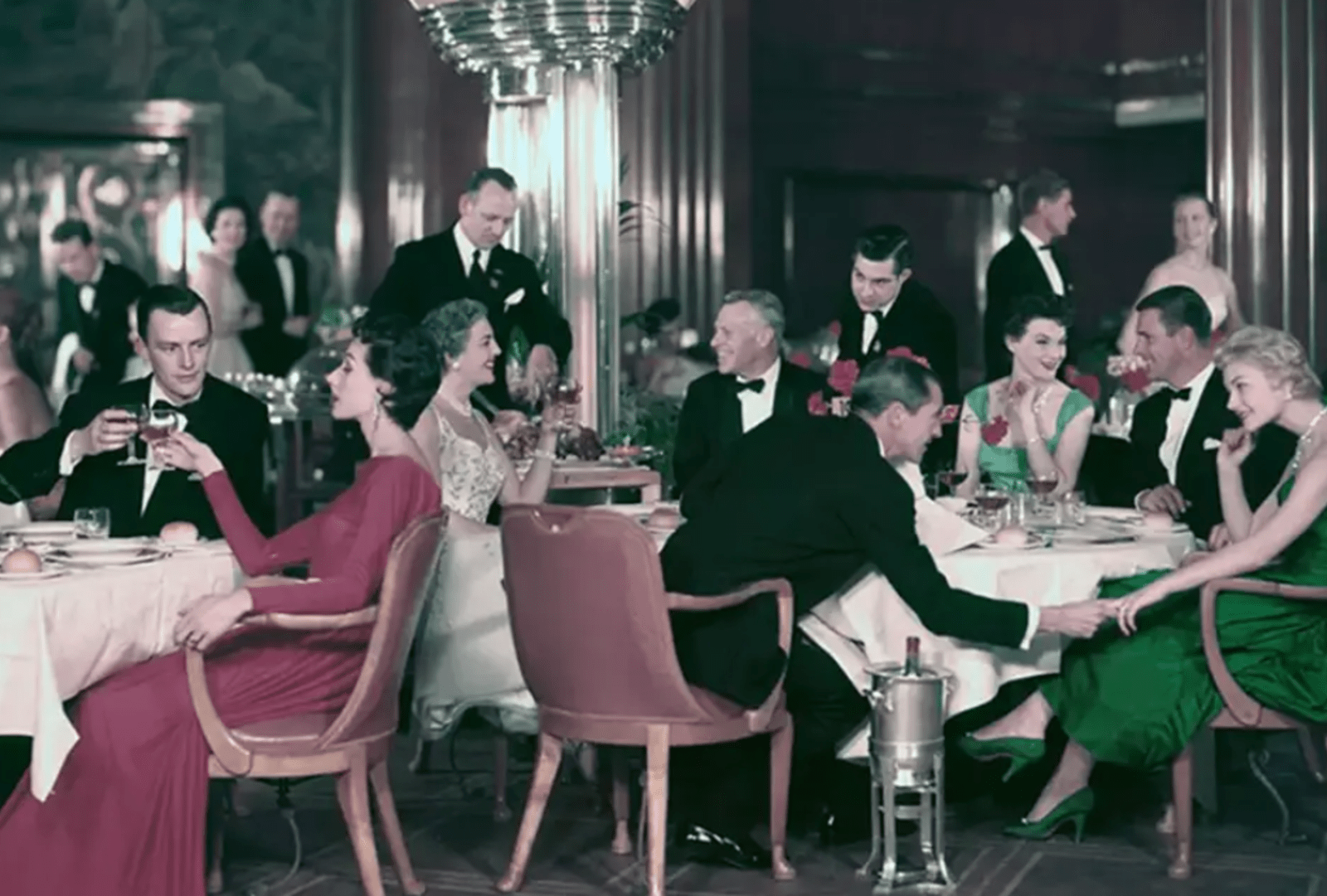 Well dressed people circa 1940s gather for dinner in a cruise ship's grand dining room