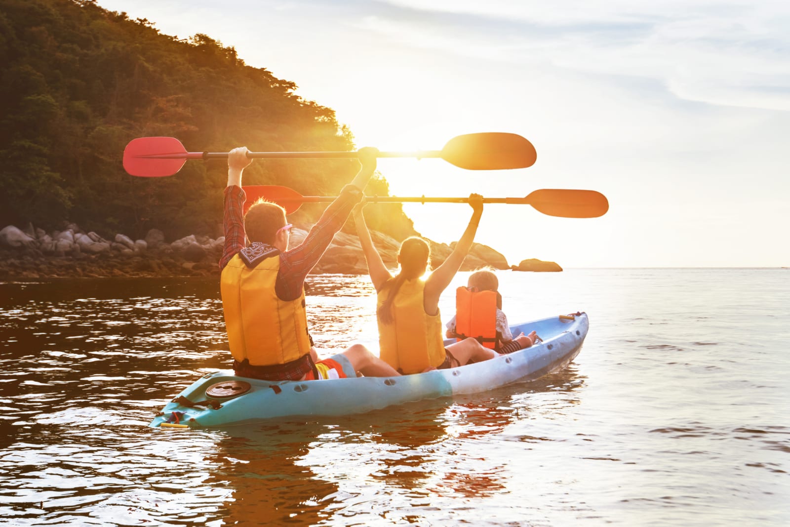 family kayaking at sunset with mountains in background