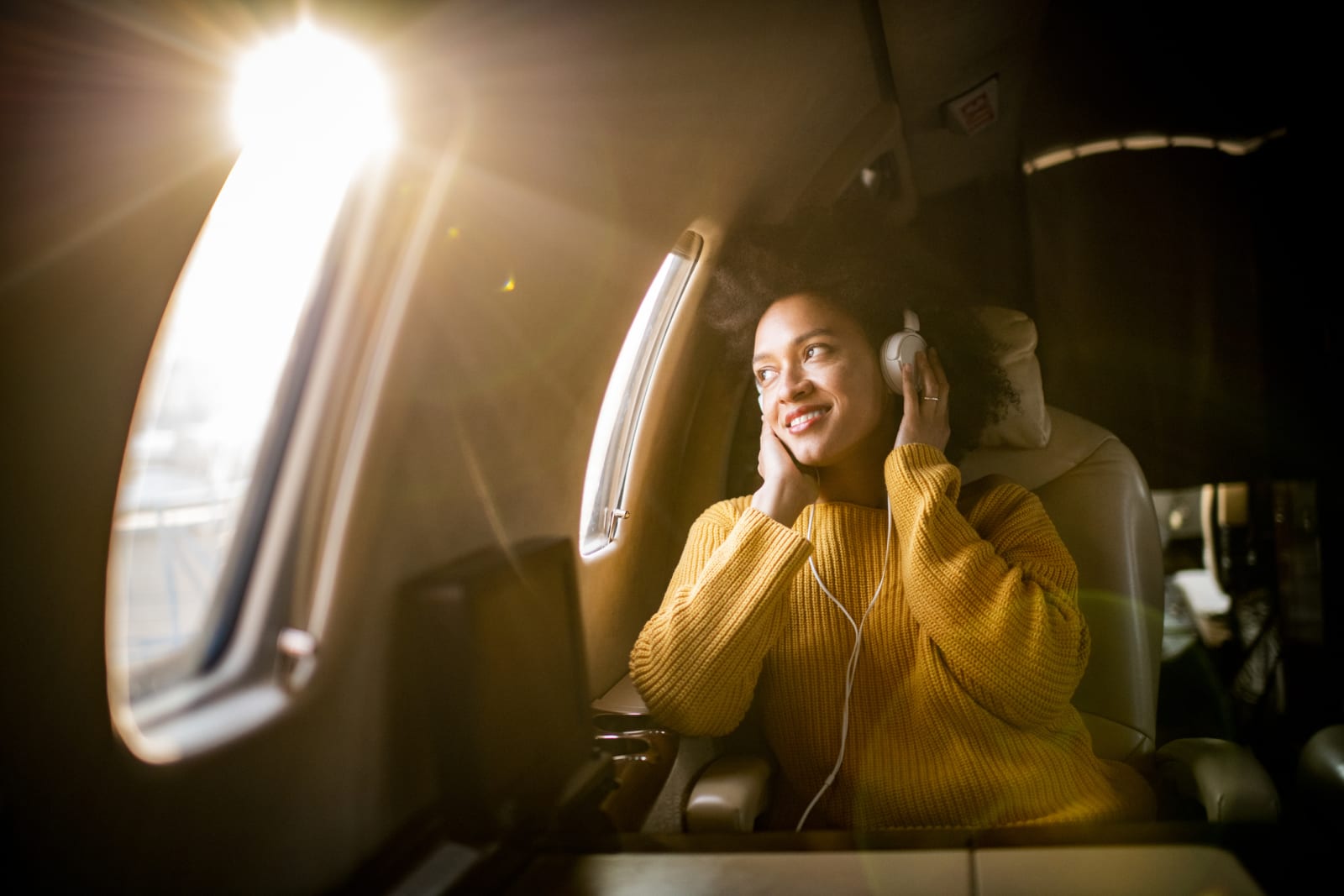 Mixed heritage woman wearing headphones on airplane