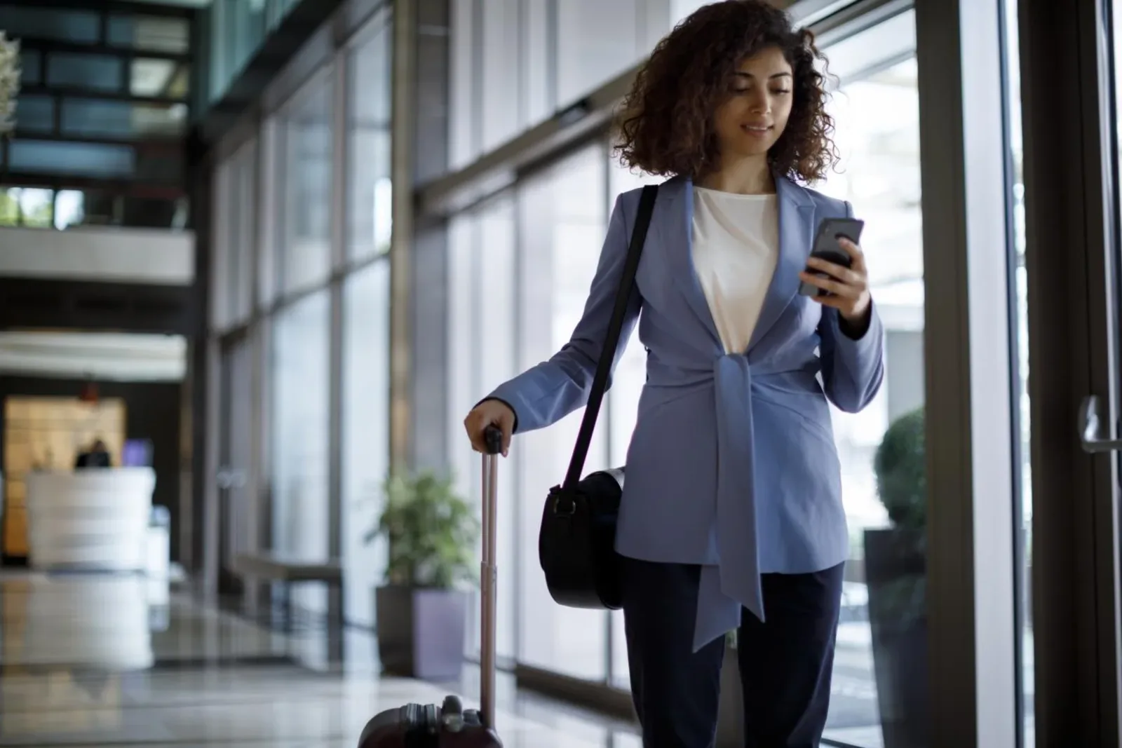 a lady is holding a luggage and using mobile phone