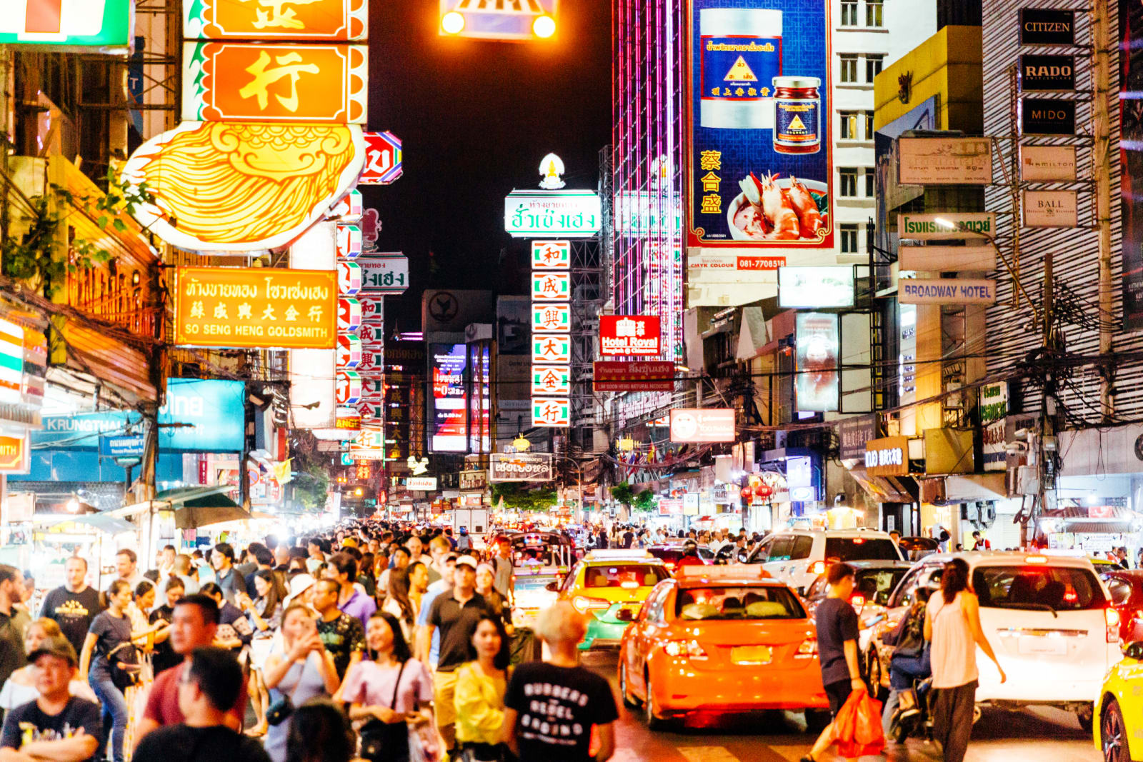 busy street in thailand full of cars, people and signs