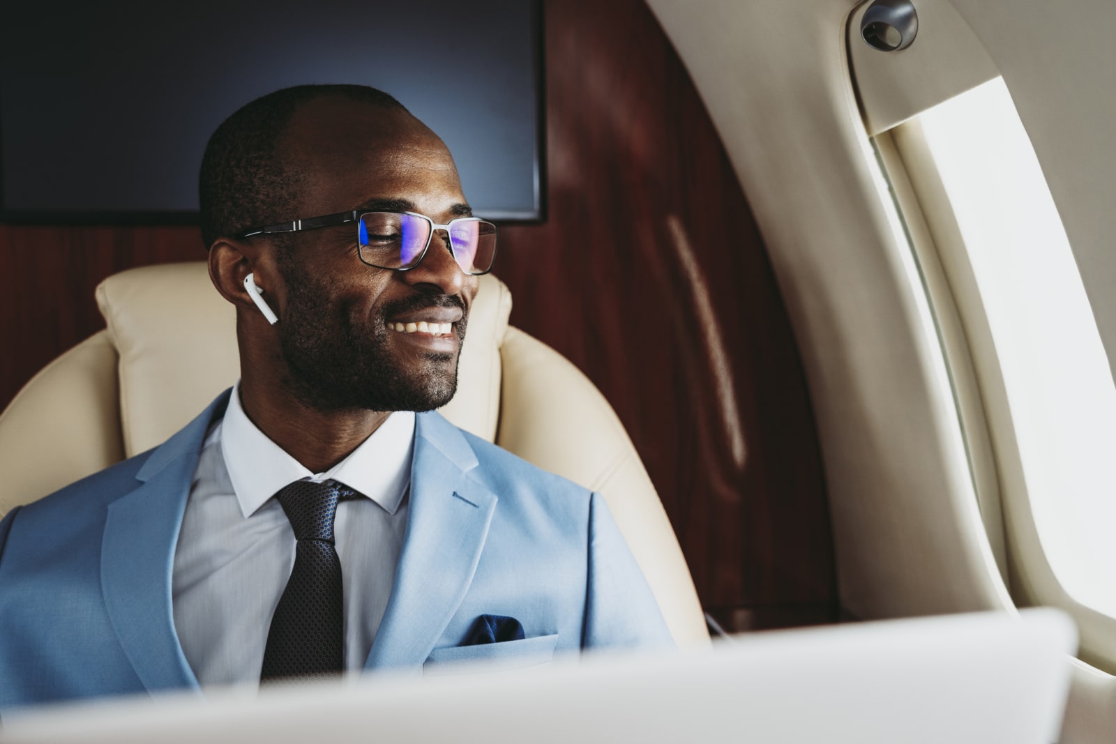 person with ear buds in sitting in plane looking out window