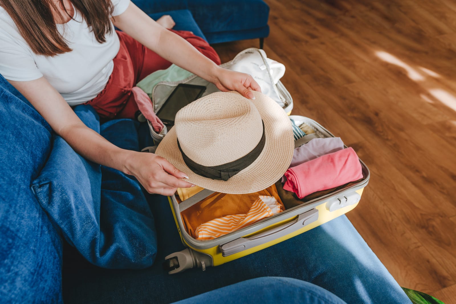 lady unpacking suitcase while sitting on couch