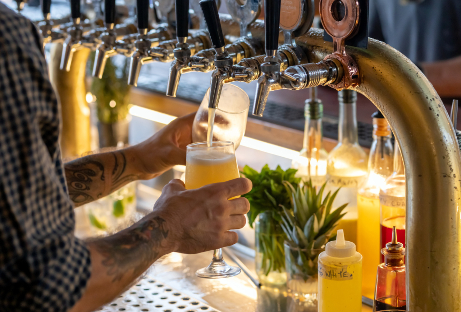 A barman pours beer from a tap at a rooftop bar