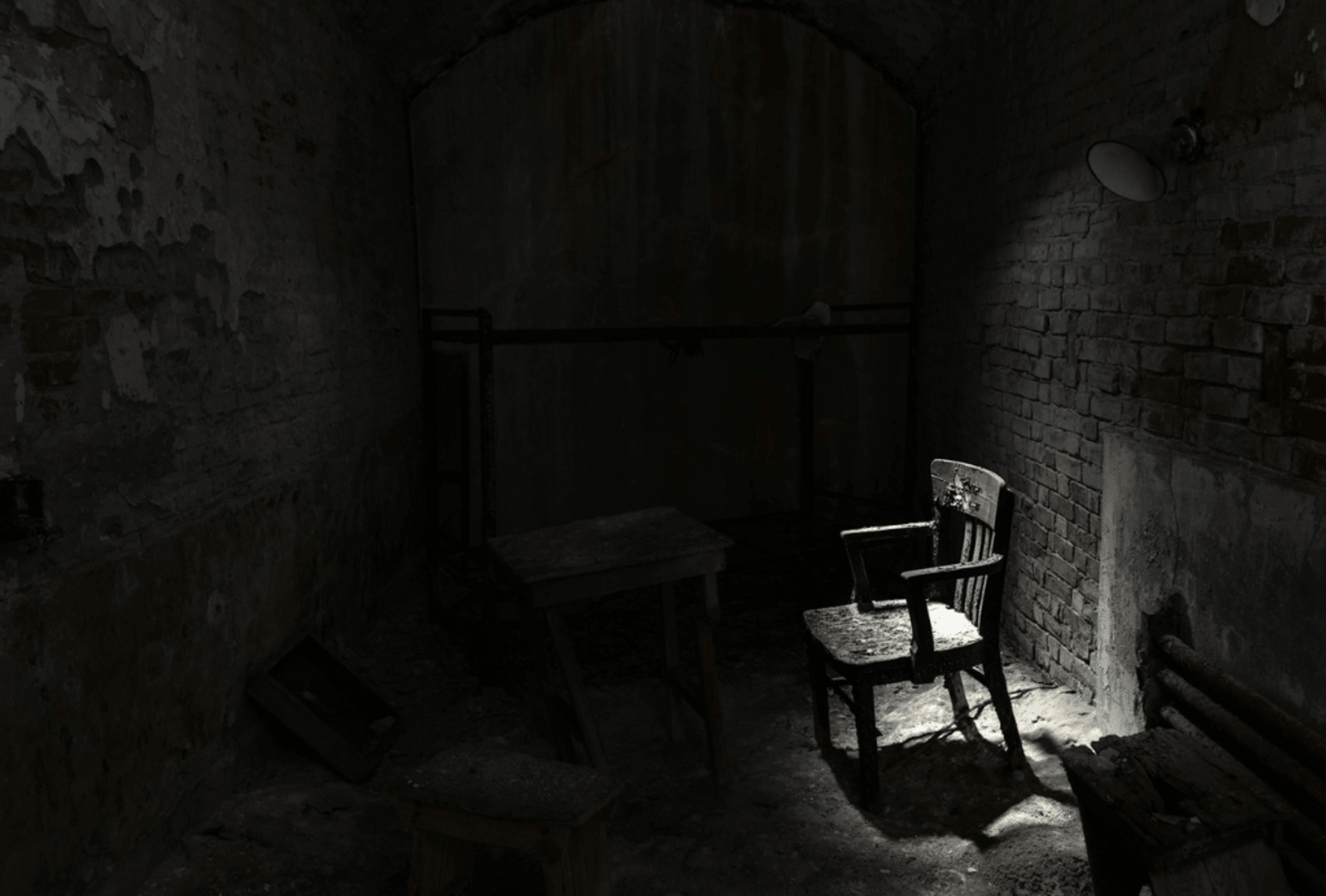 An eerie lamp lights up a derelict chair in a condemned room