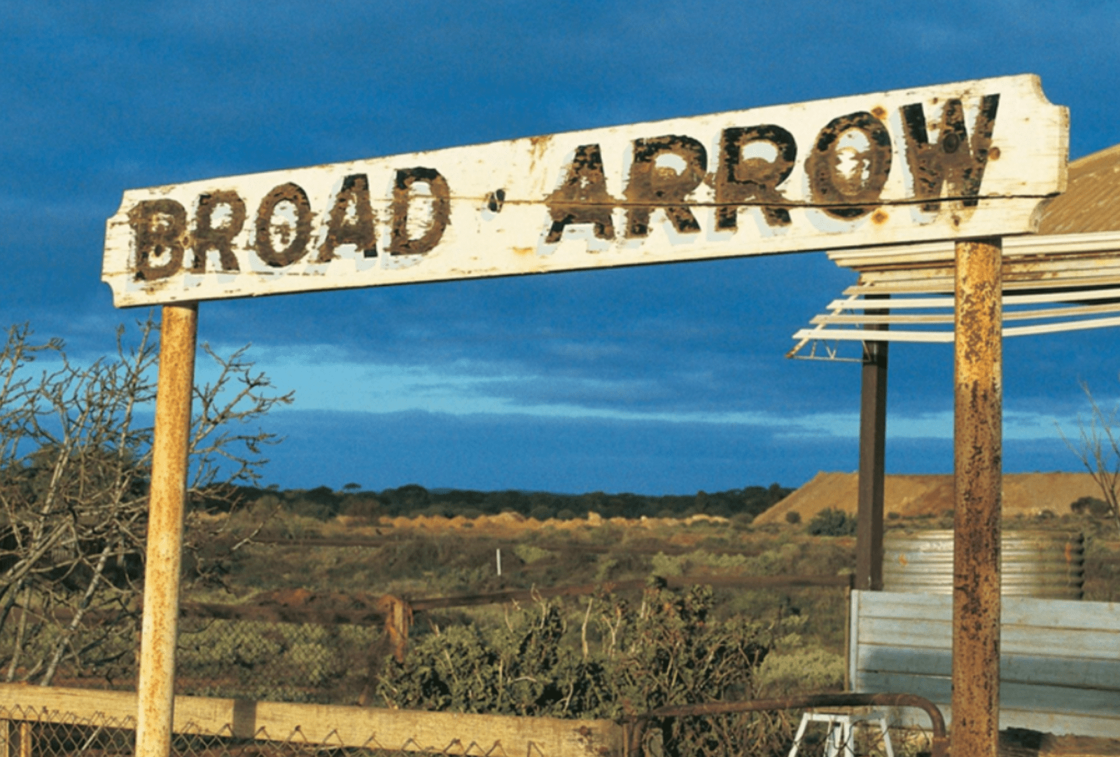 An old road sign reads "Broad Arrow" in weathered lettering