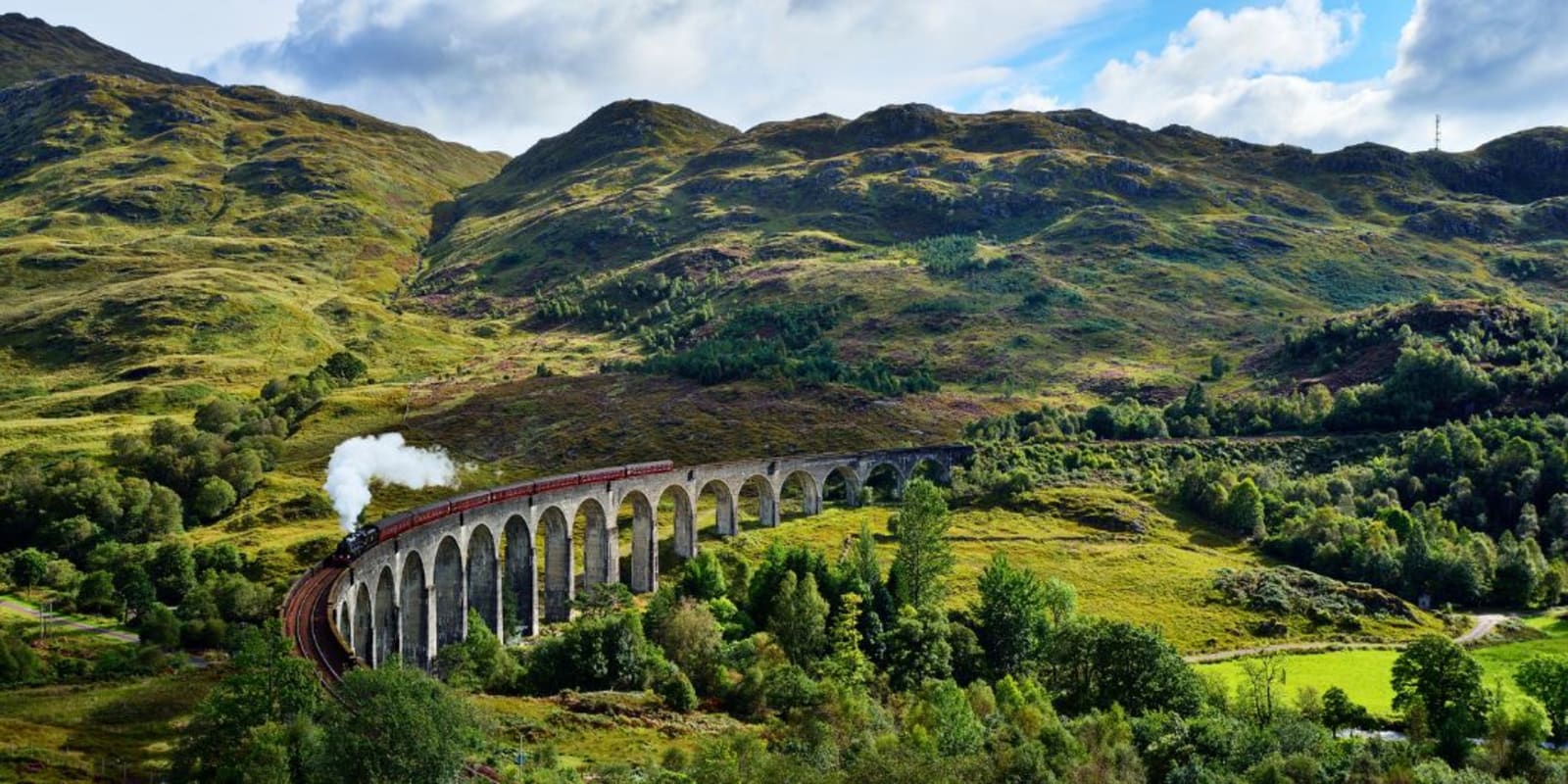 A long steam train travelling over the Glenfinnan Viaduct