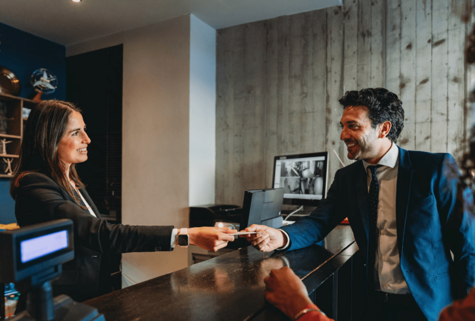 Hotel reception handing over the room key to a couple of guests