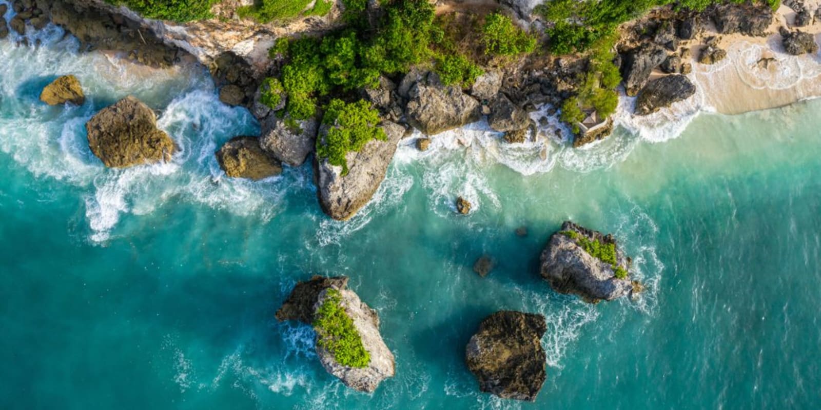 Overhead view of waves breaking near a cliff with a beach