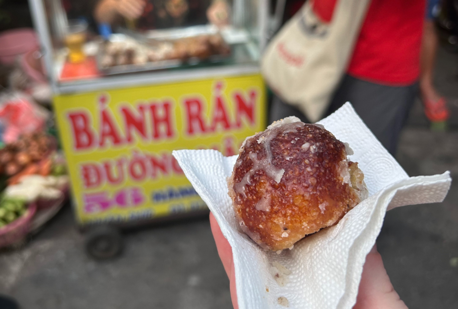 A banh ran hot off the street cart is served up in a paper napkin
