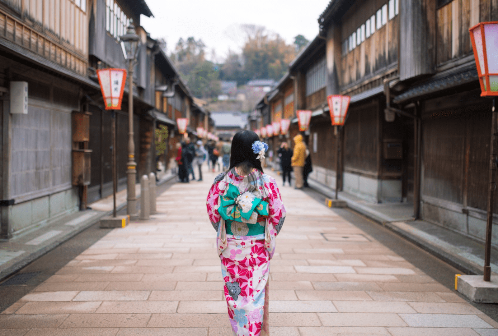A woman in traditional Japanese costume walks down a quiet backstreet.