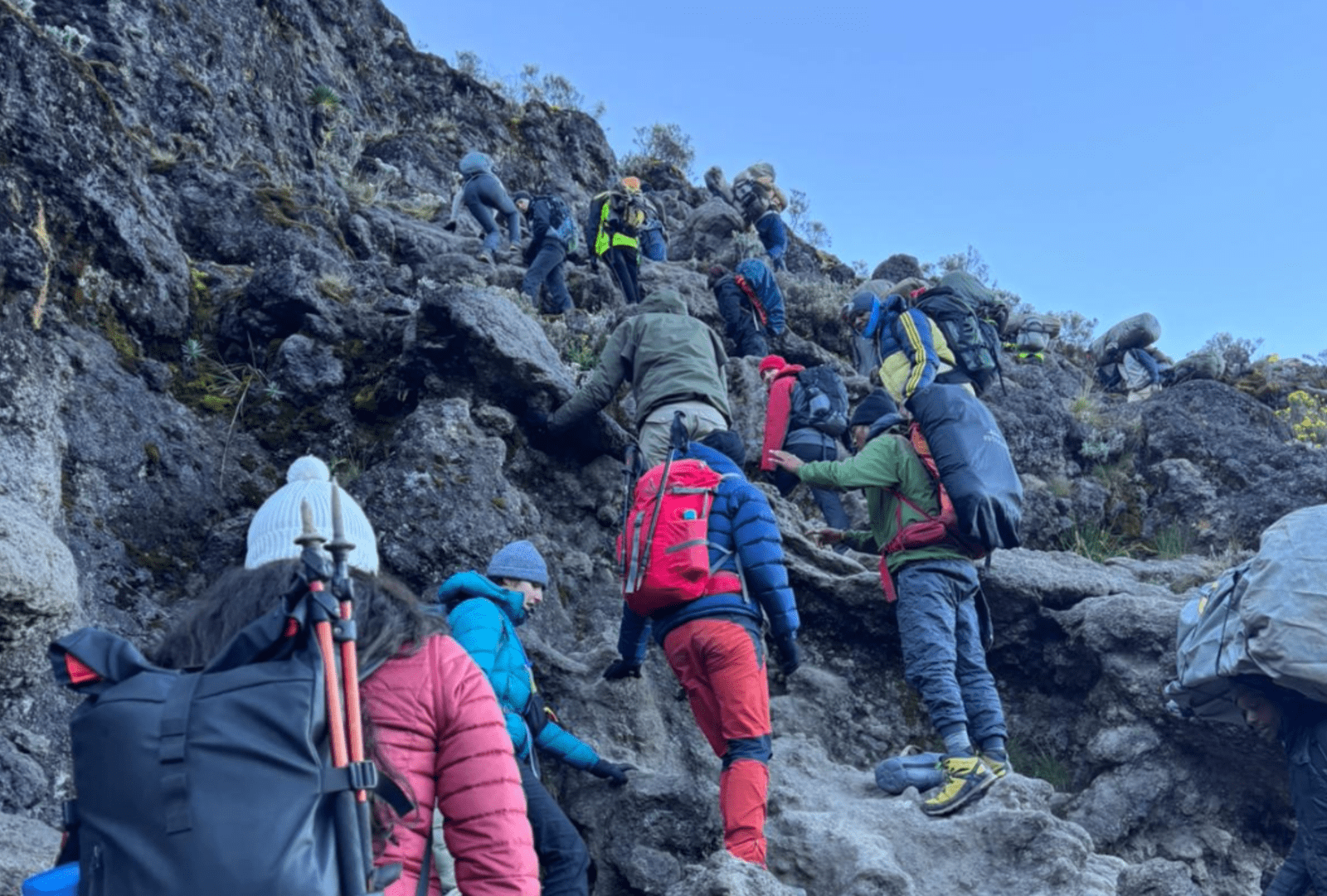 Hikers negotiate a steep path over rocky terrain on their way up Mount Kilimanjaro