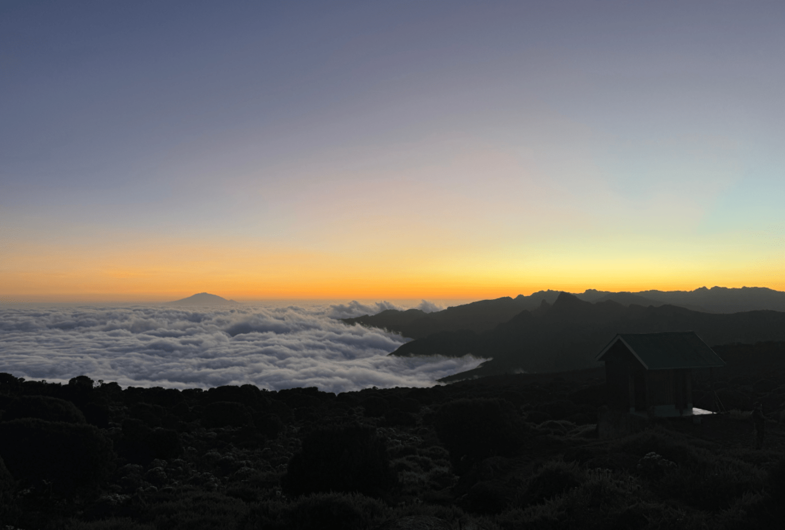 A layer of cloud viewed from above gathers around the foothills of Mount Kilimanjaro