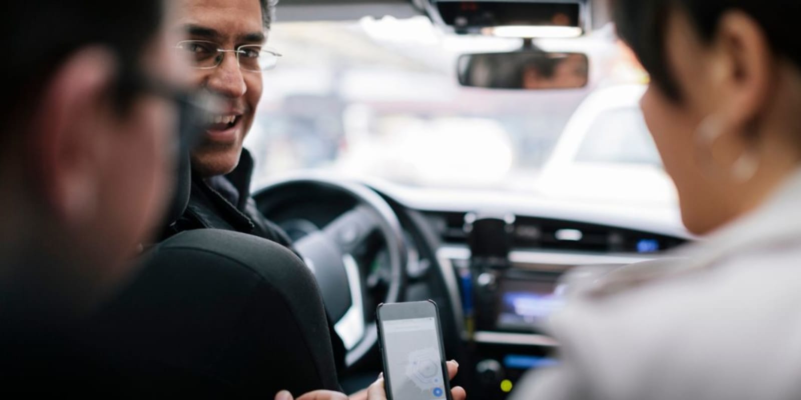 Two people in the back of a taxi communicating with the driver