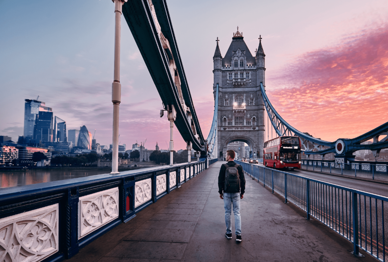 A man walks over Tower Bridge during a colourful London sunrise
