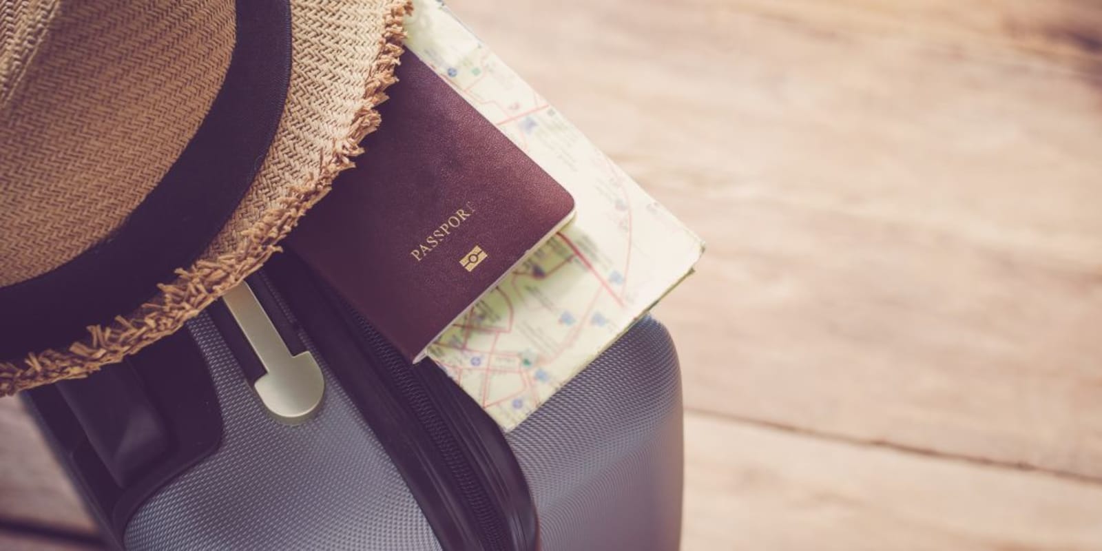 A hat, passport and other travel documents sitting on top of a suitcase