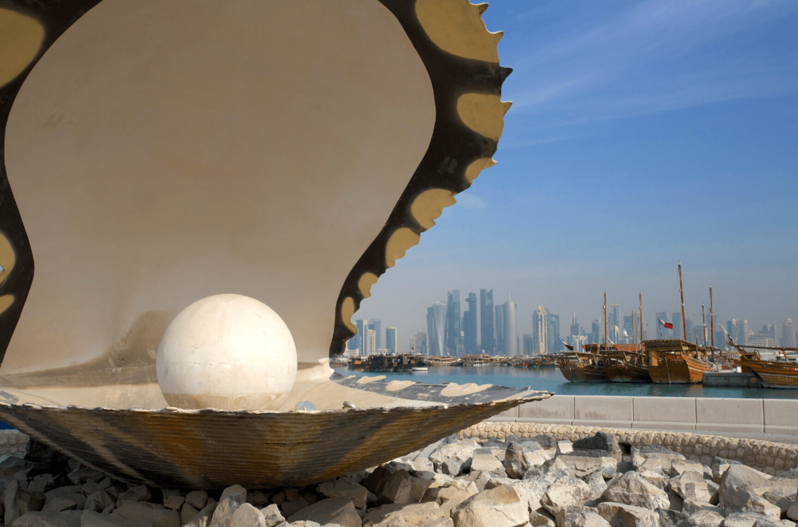 Giant pearl and clam statue with skyscrapers and boats in the background