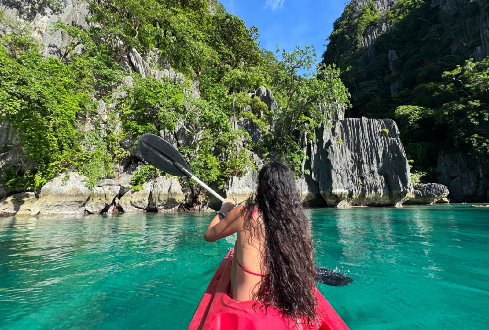 Kayaking the still, green waters around the rocky shoreline of Palawan Island