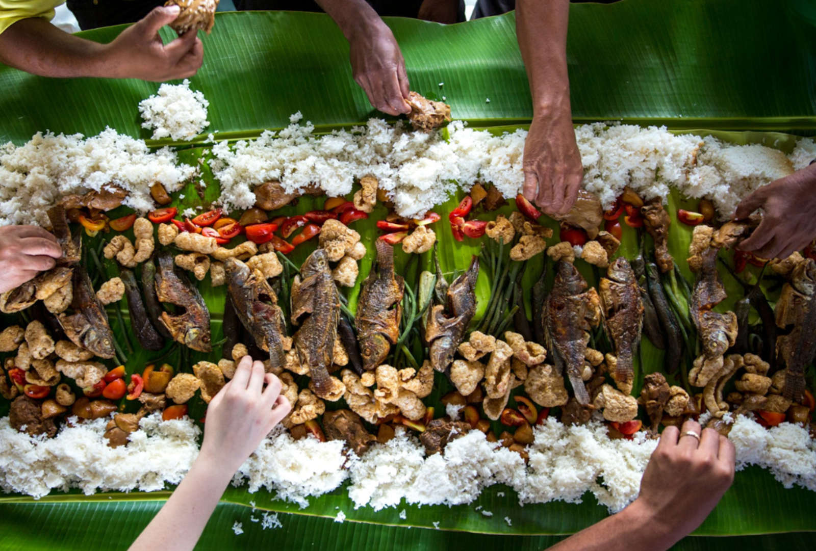 A traditional Filipino feast is shared by many hands