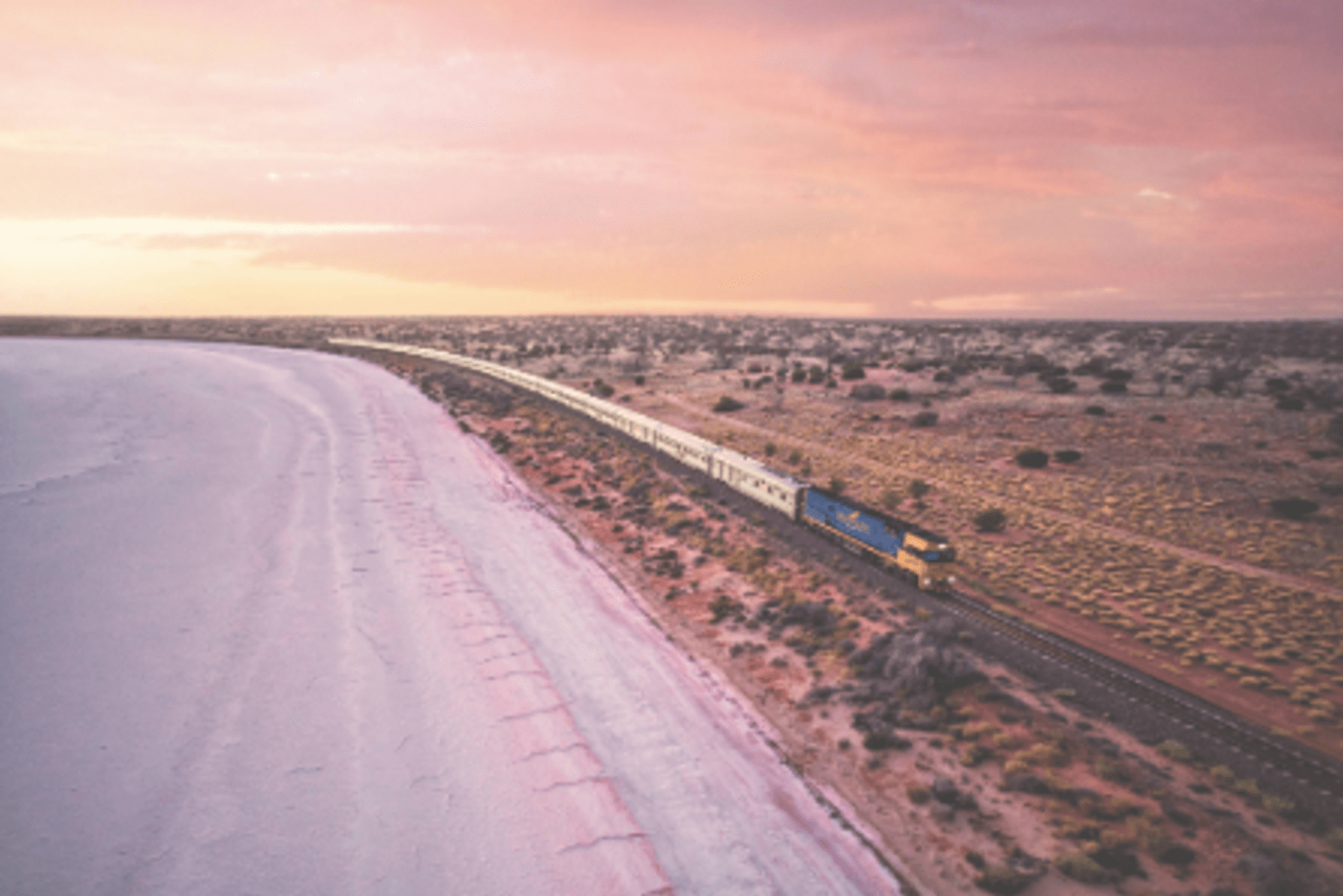 Train travelling along australian outback at sunset
