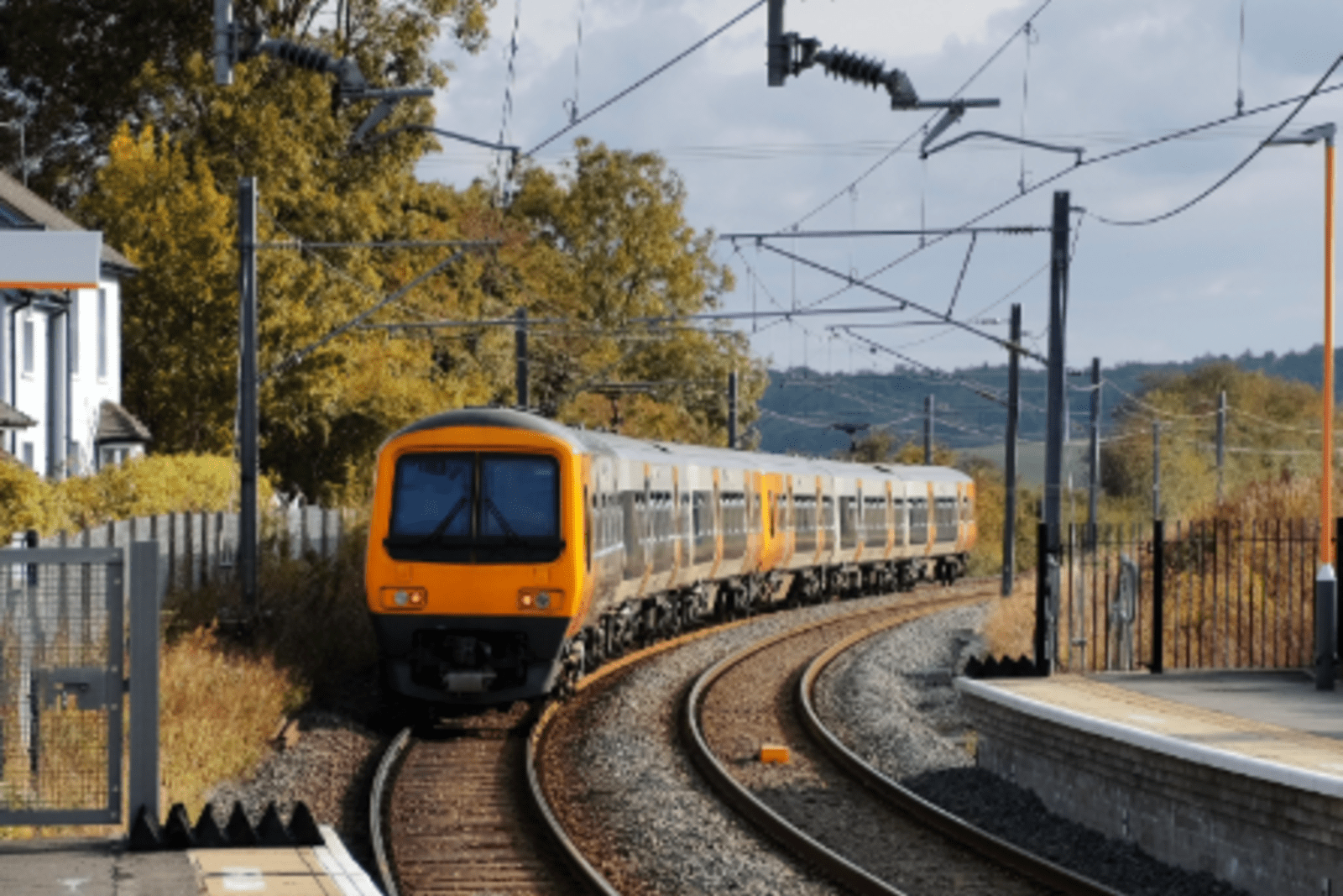 britrail train coing into station in the uk surrounded by trees