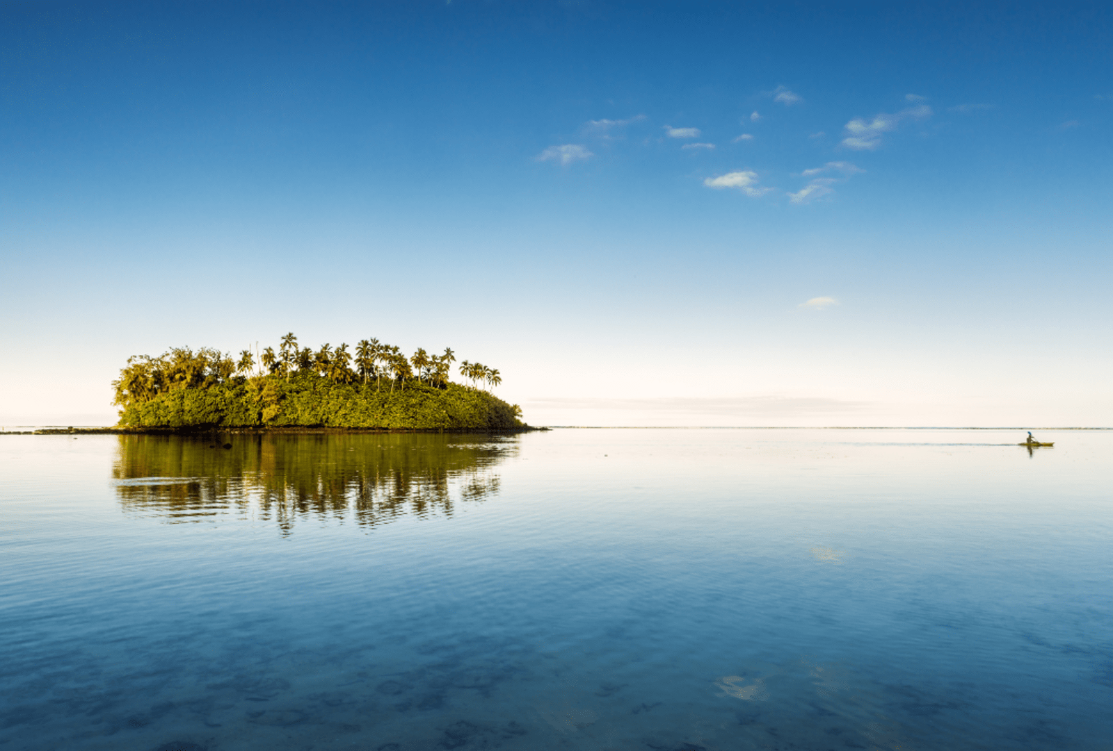 An islet on the horizon of glassy-still lagoon