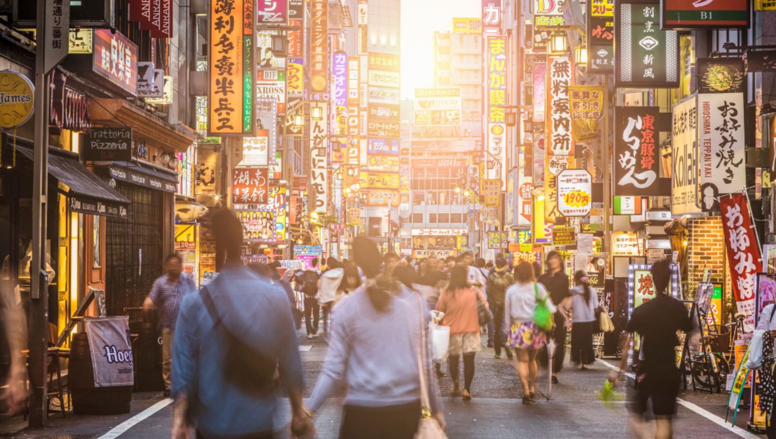 crowd walking down Shinjuku street at sunset 