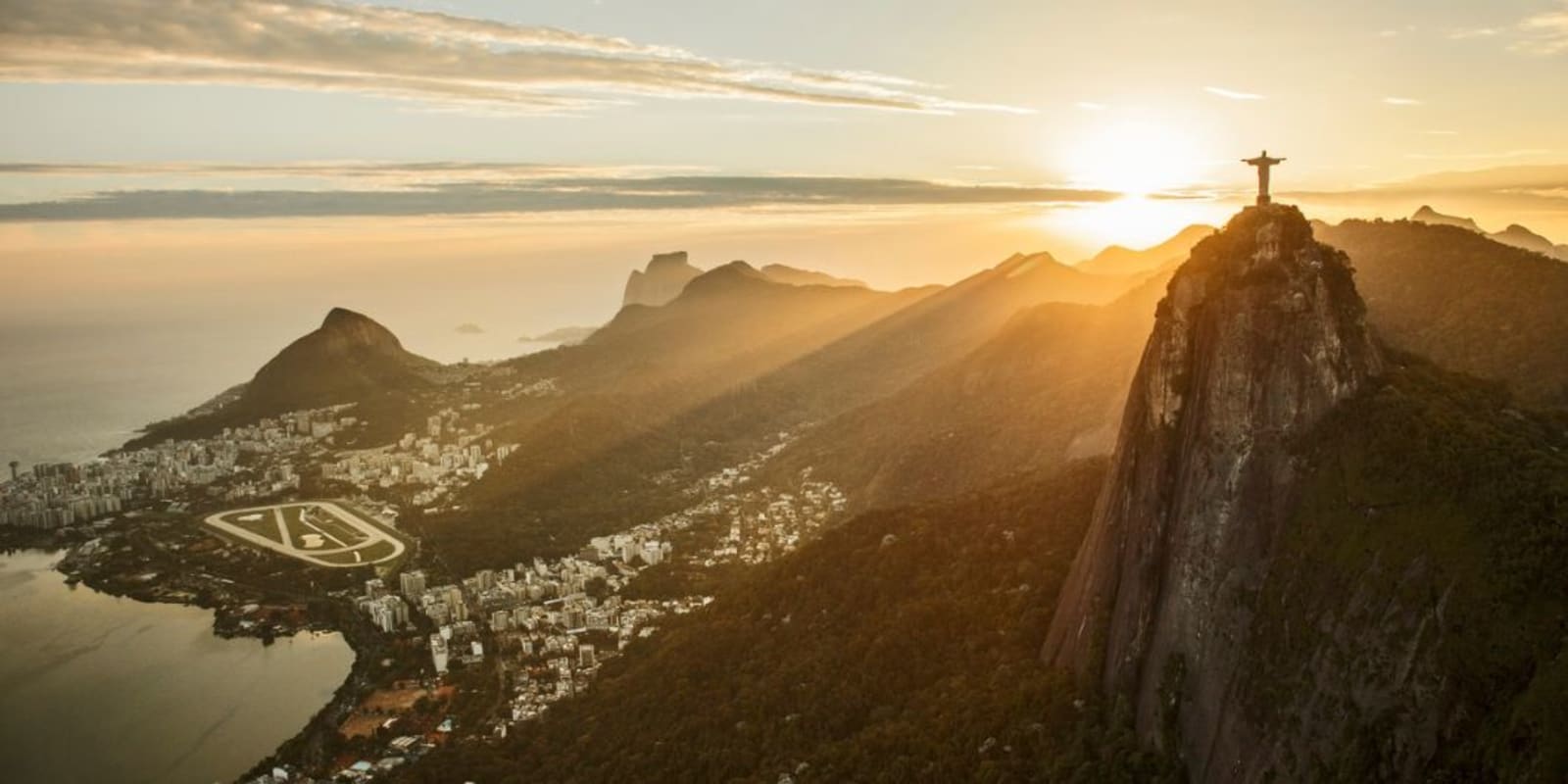 A long shot of the sun setting behind the Christ The Redeemer statue in Brazil