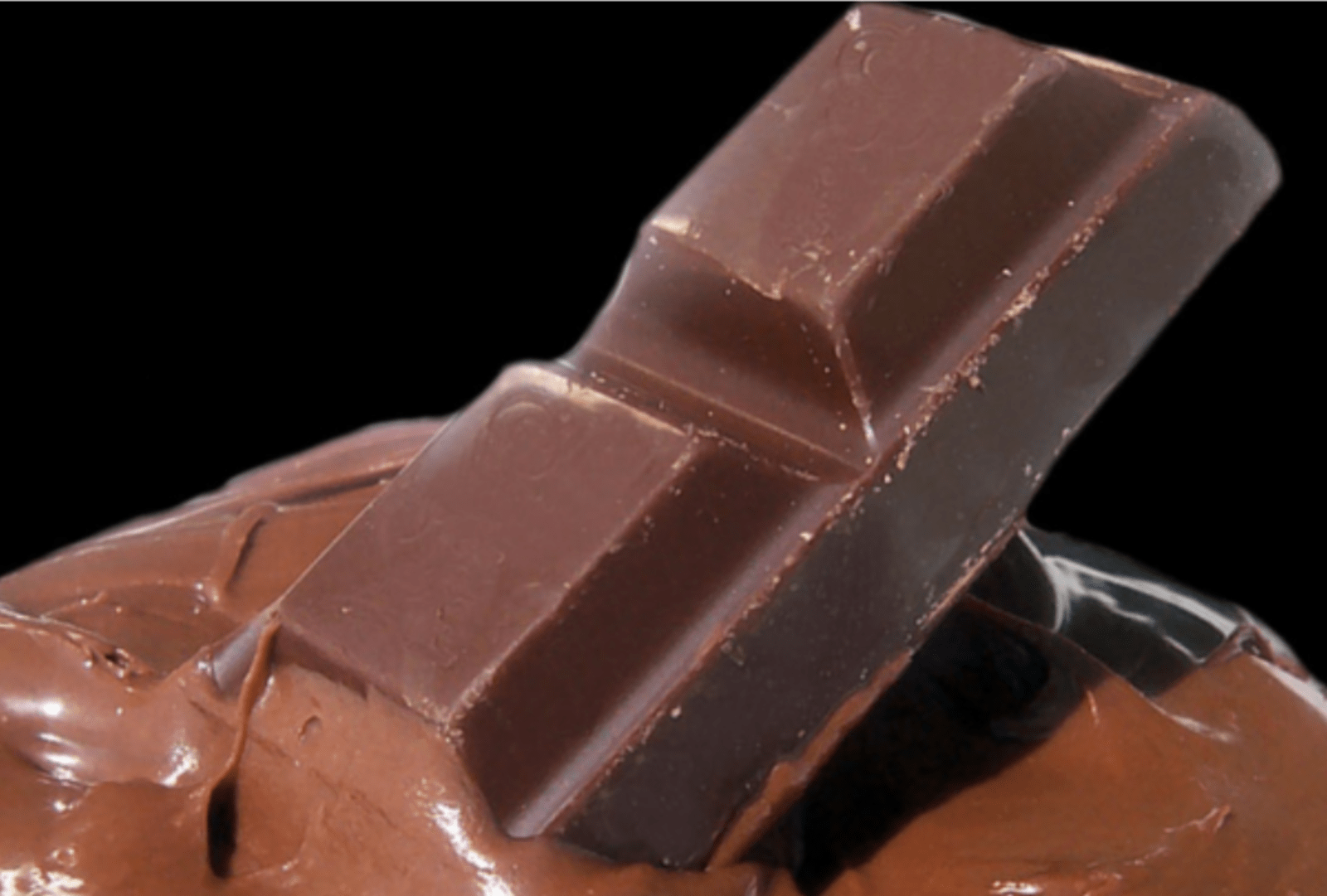 A chunk of chocolate sinks into a mound of molten chocolate