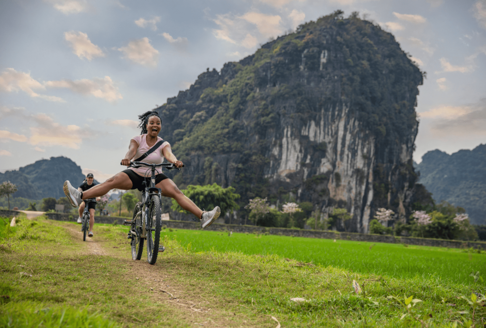 Woman laughs while doing a trick on a bicycle in a field
