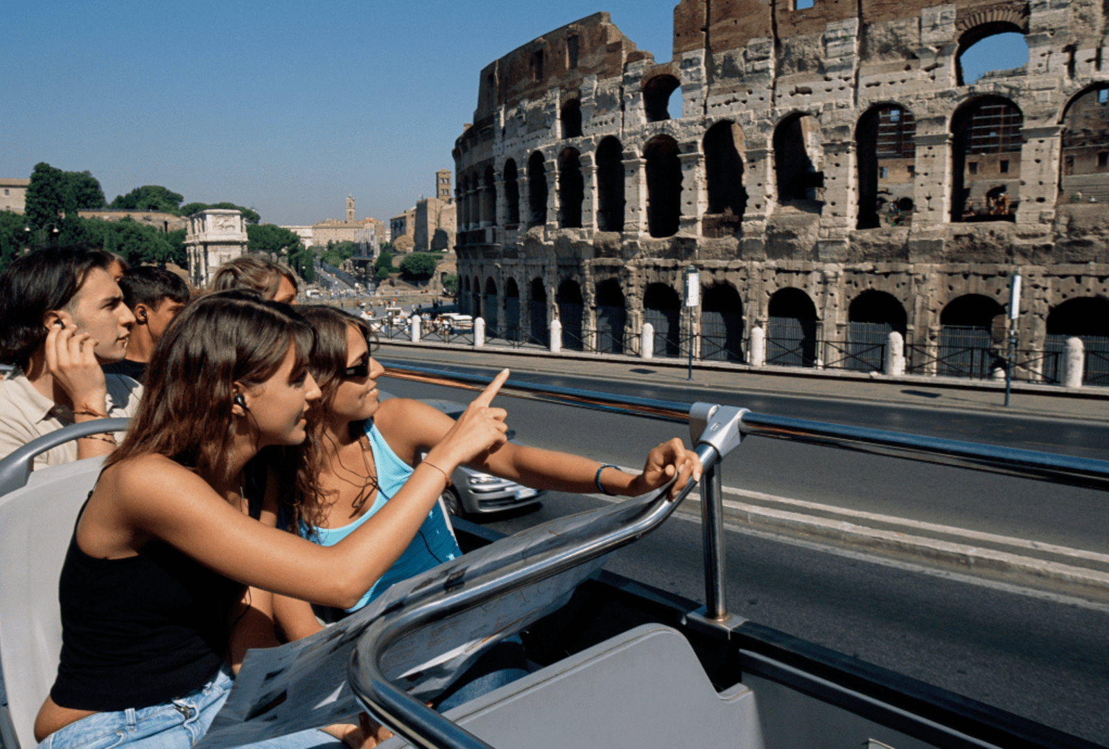 People look at colosseum from a tour bus
