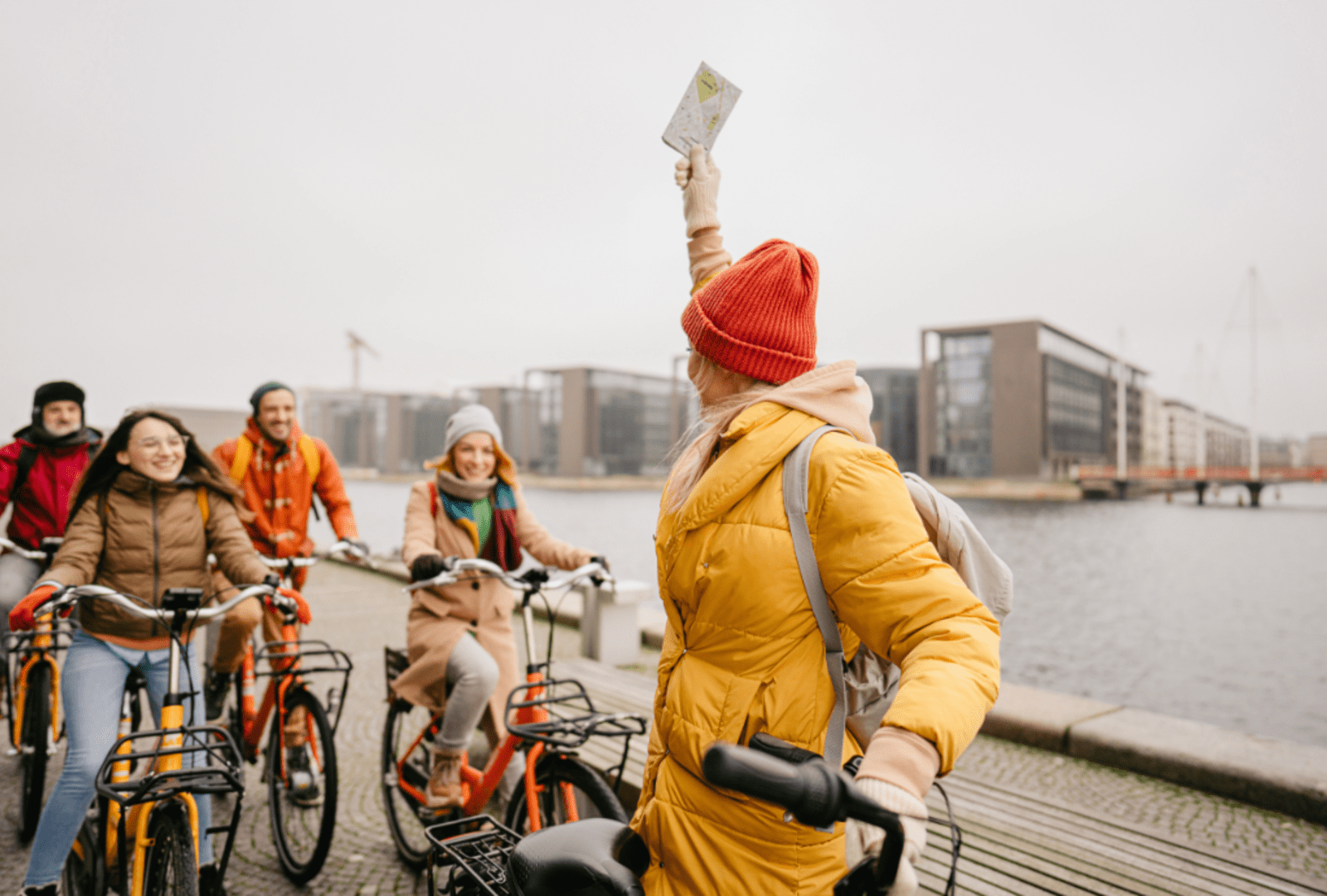 A group of young people laugh while riding bikes down a wharf