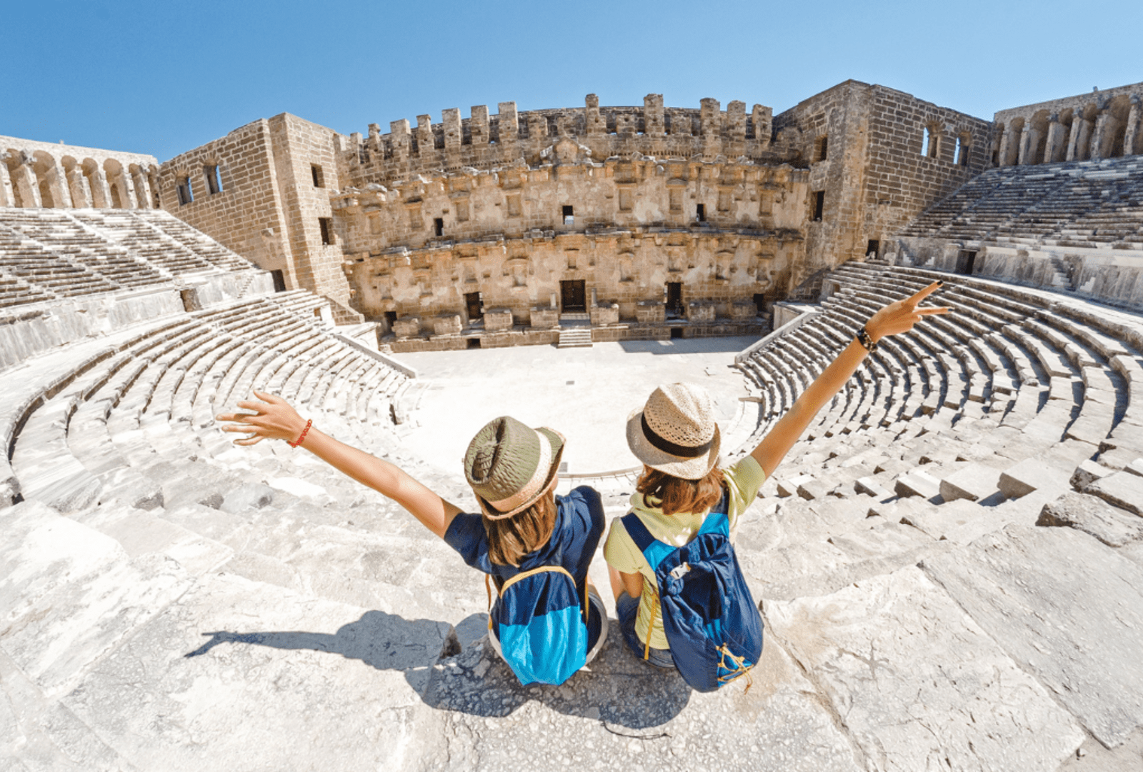Two women stand with their arms up in the colosseum
