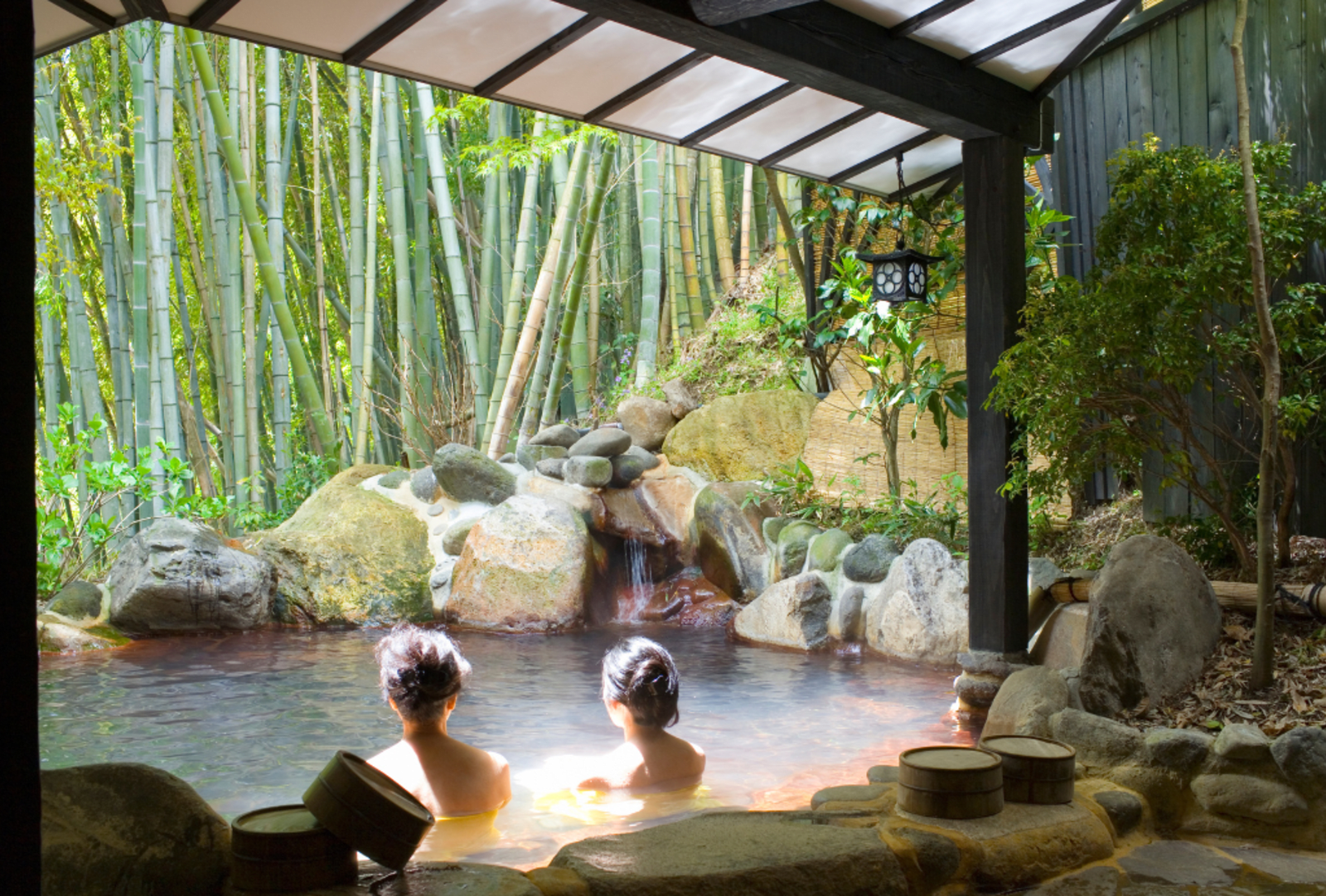 Two women bathe in an outdoor onsen pool