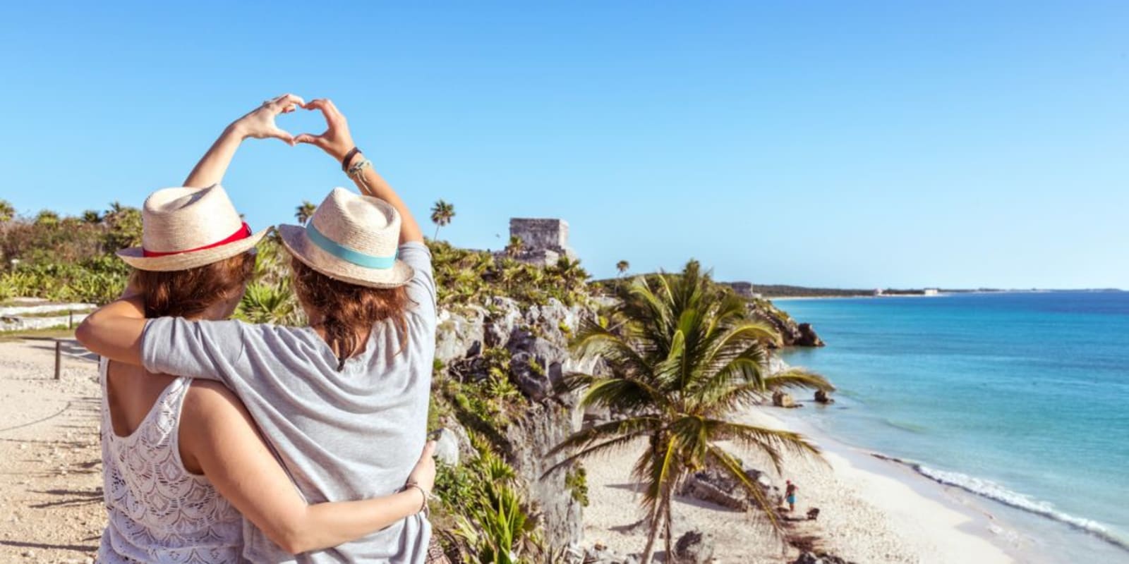 Couple making a heart sign with their hands overlooking the beach