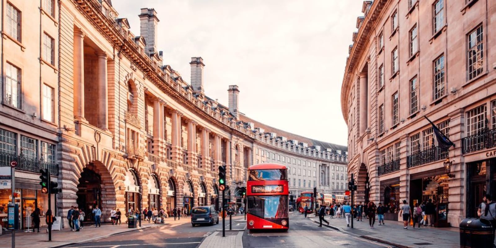 A red double decker bus driving down a street in London