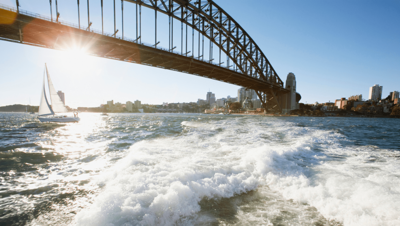 boat moving through water under sydney harbour bridge